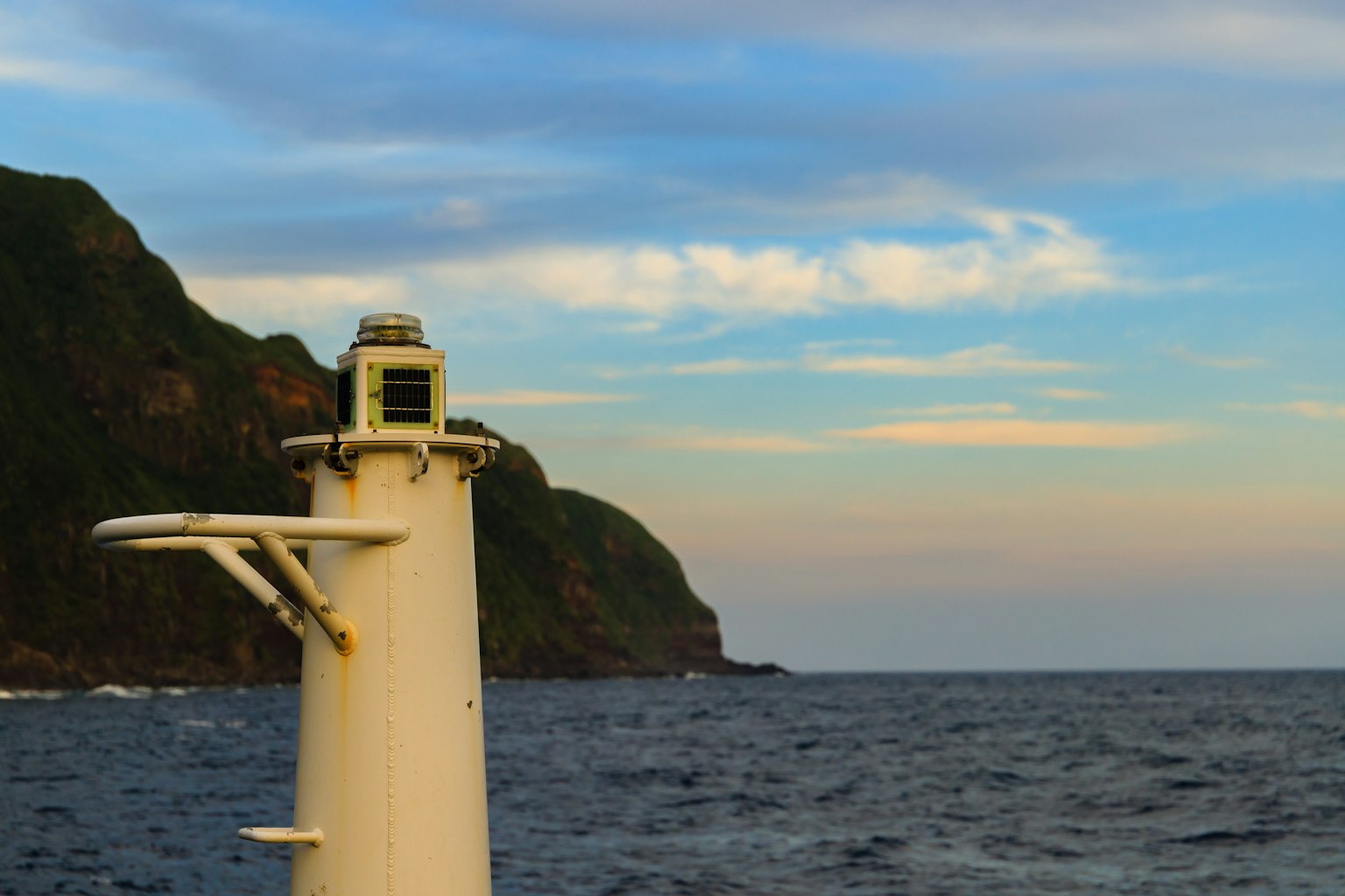 Side view of a lighthouse with ocean and mountain background