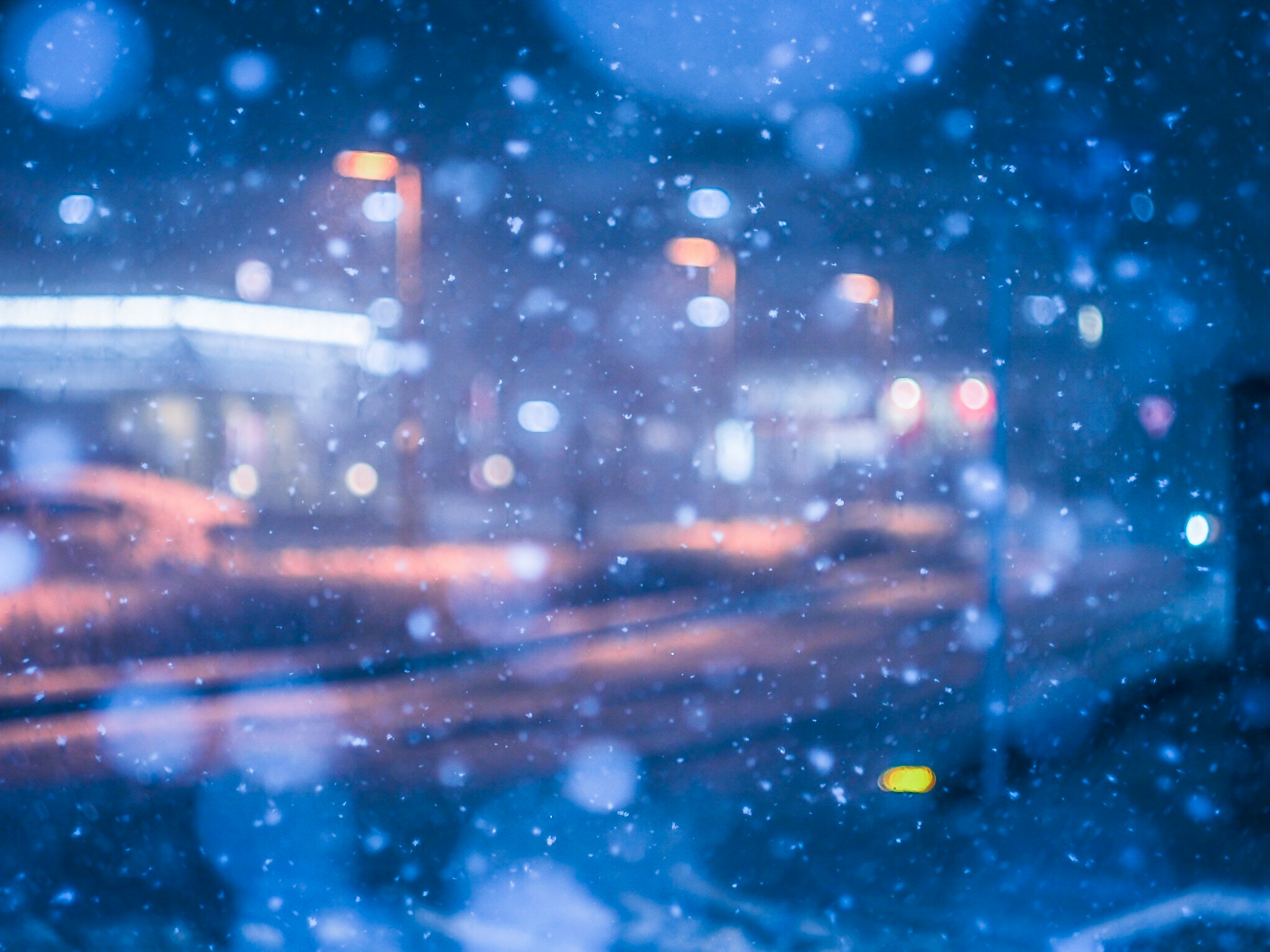 降る雪の夜ににぎわう街の道路と信号