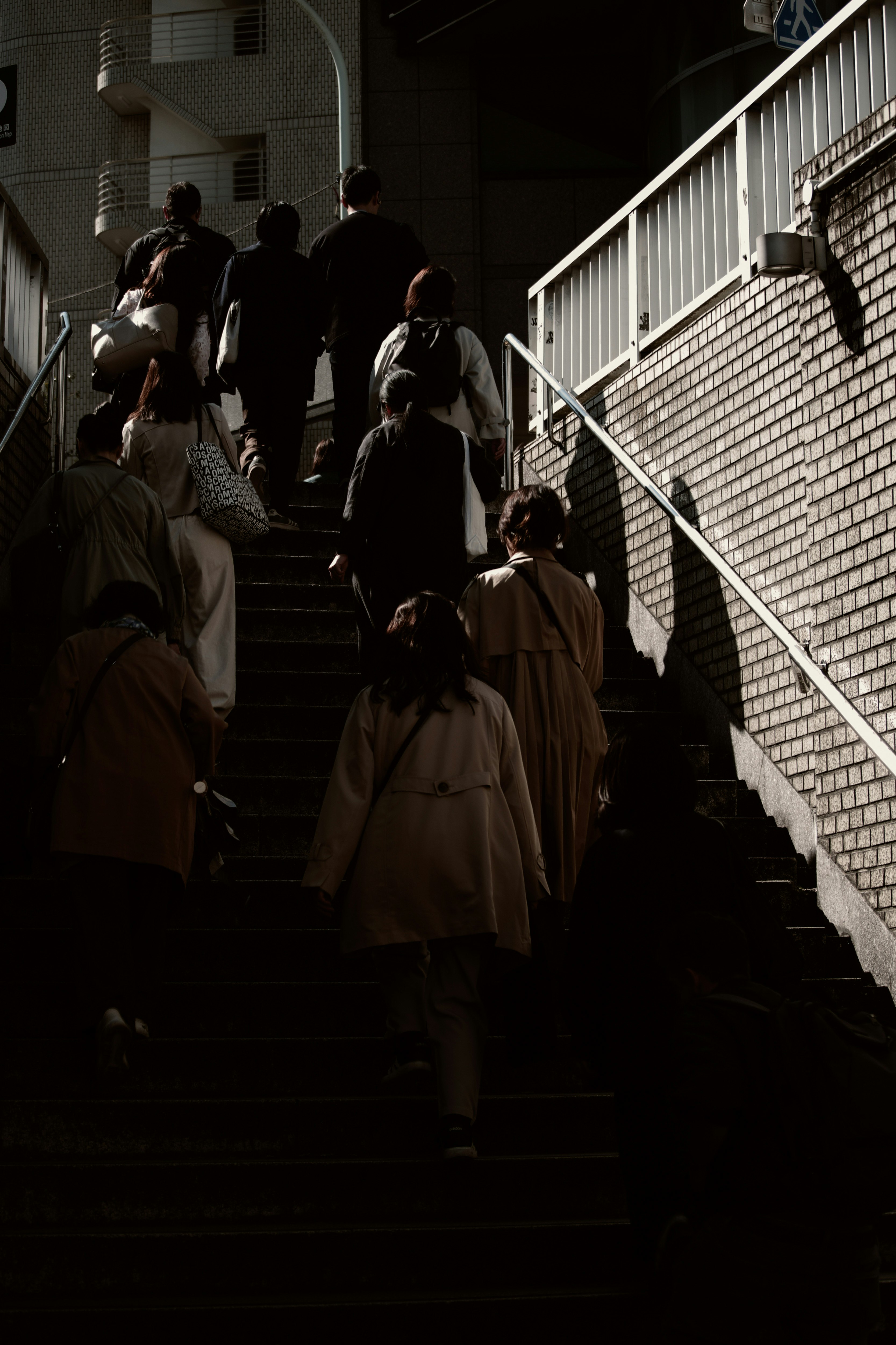 階段を上る人々のある駅前の街並み