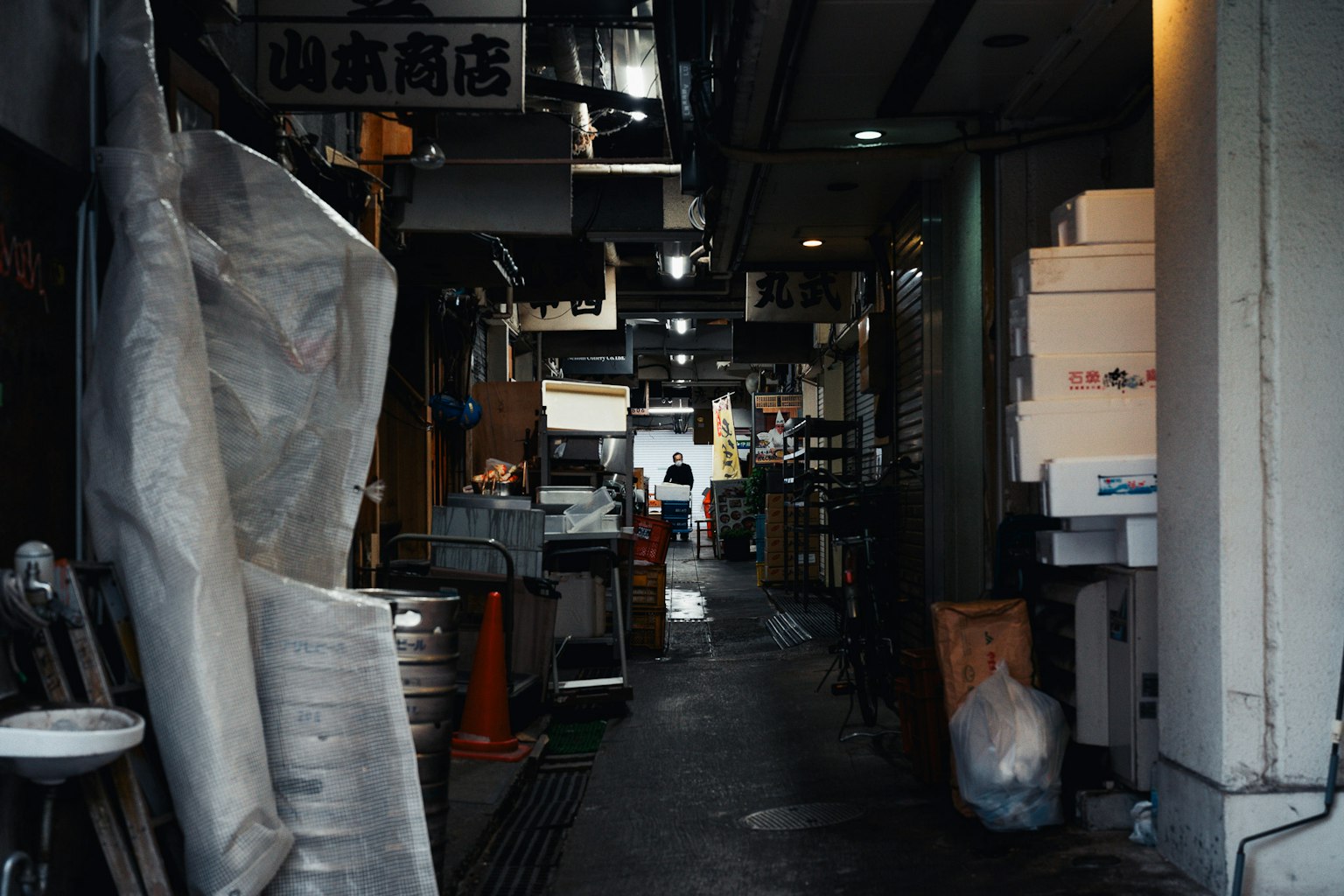 Callejón estrecho con tiendas y objetos apilados característicos de un mercado japonés