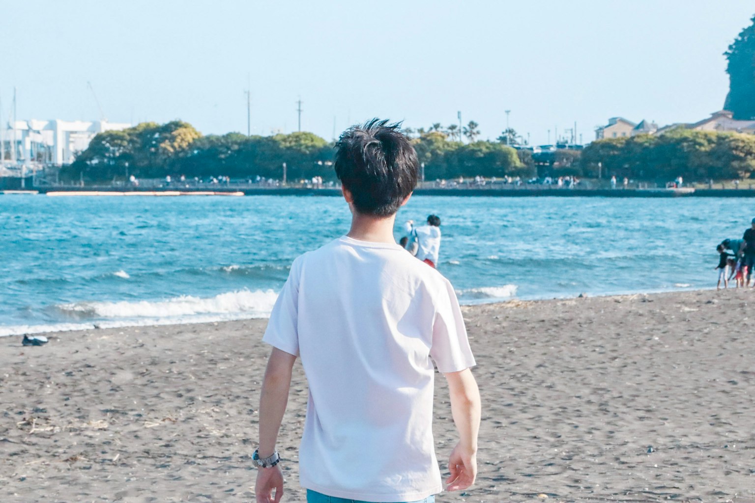 ชายหนุ่มเดินอยู่บนชายหาดพร้อมทิวทัศน์ของทะเลสีฟ้า