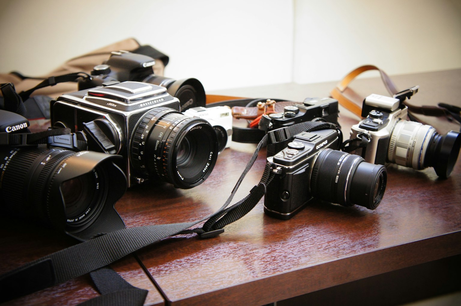 Mehrere Kameras auf einem Holztisch mit einer Mischung aus Vintage- und modernen Designs