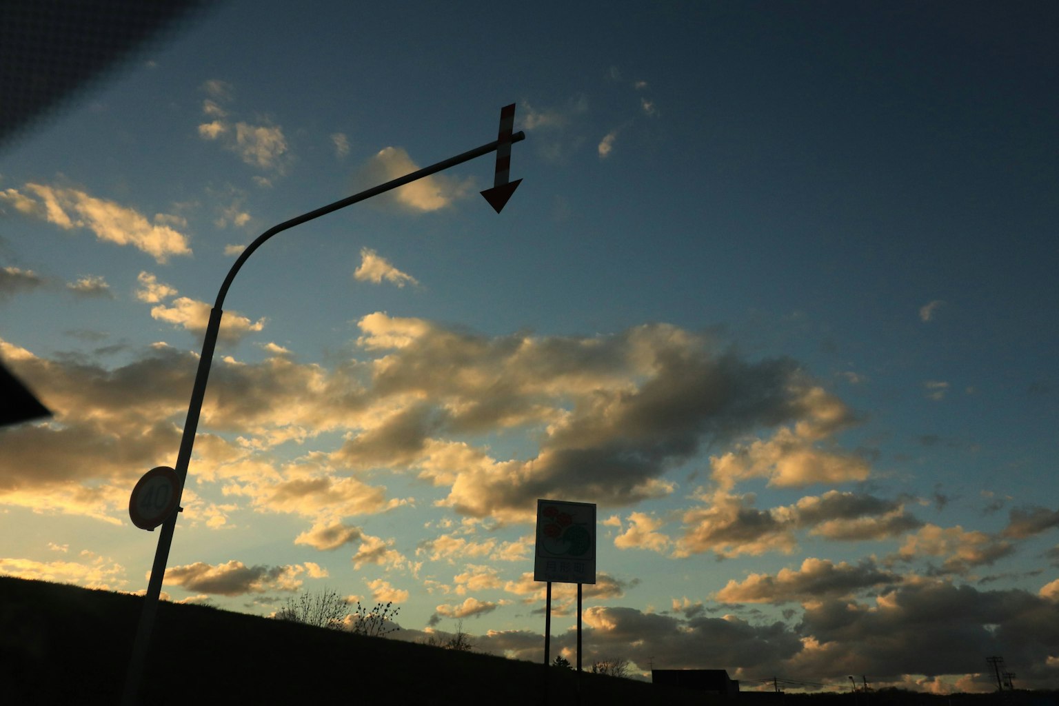 Eine Szene mit einem gebogenen Verkehrsschild vor einem Hintergrund aus Sonnenuntergangshimmel und Wolken