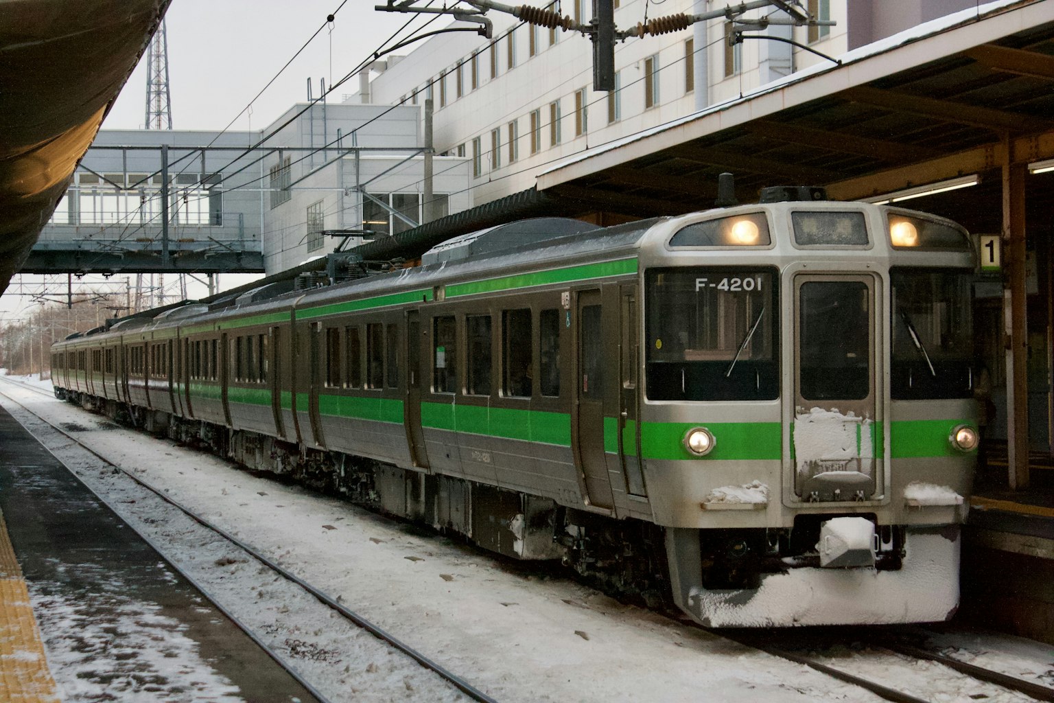 Treno con dettagli verdi parcheggiato in una stazione innevata