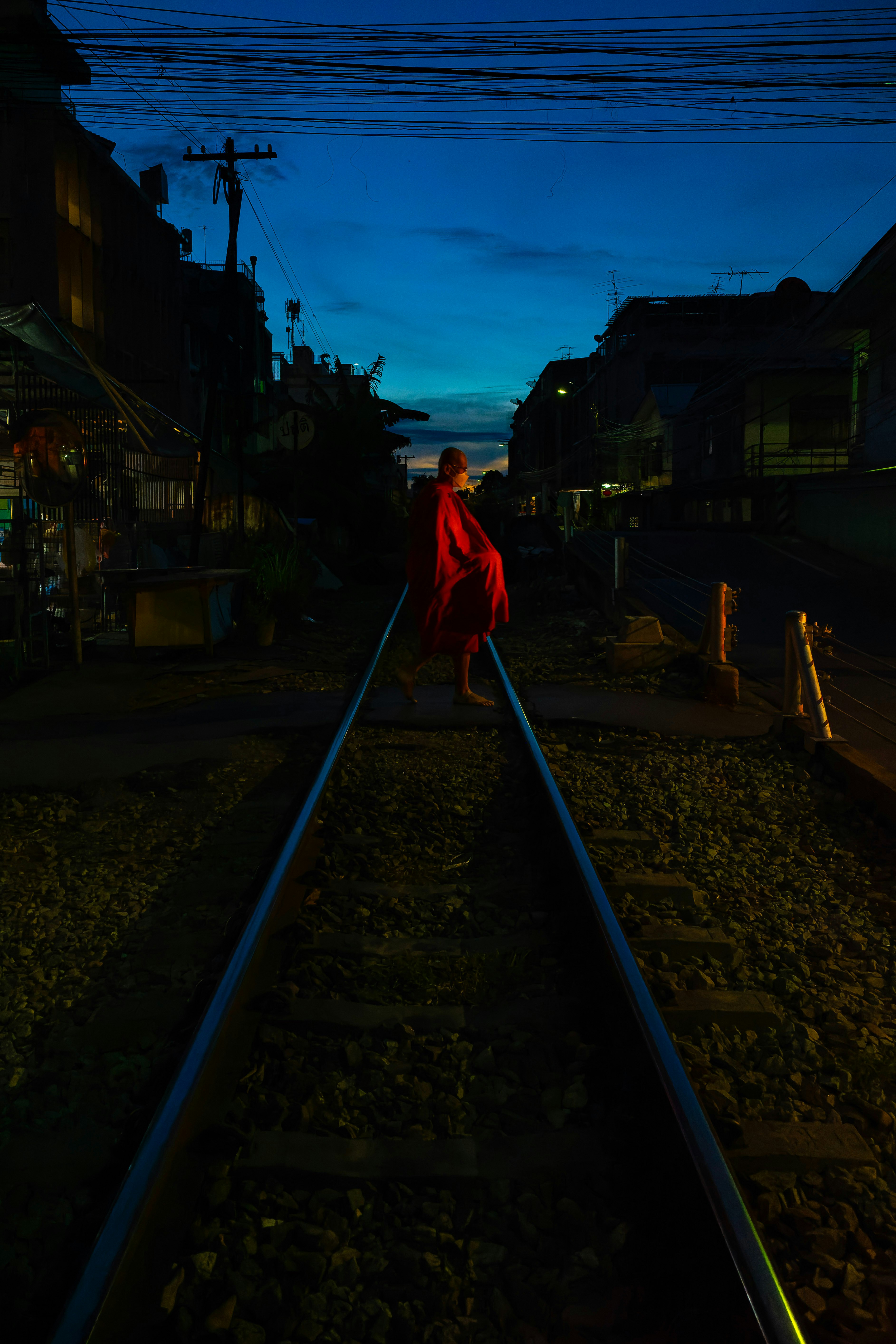 線路の上を歩く人物がいる夜の路地