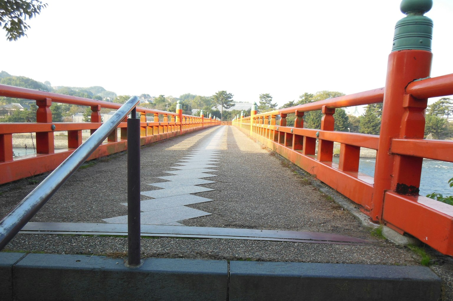 Pemandangan jembatan dengan pagar oranye dan trotoar berpola