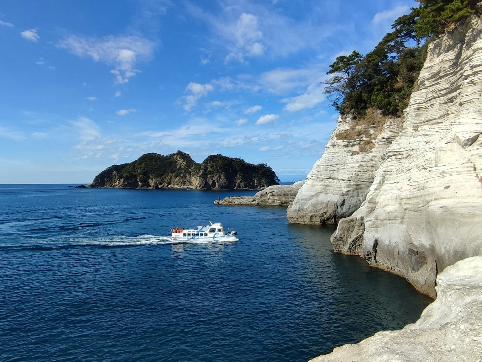 Vista panoramica di scogliere bianche e mare blu con una piccola barca che naviga