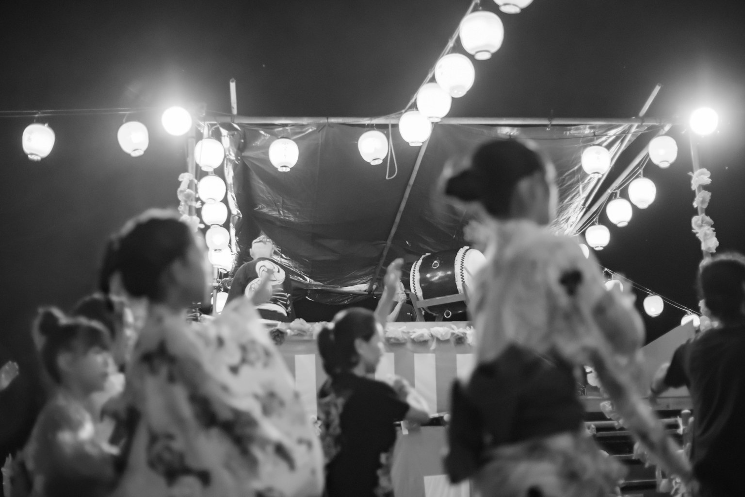 Personas bailando en un festival nocturno con luces de linternas
