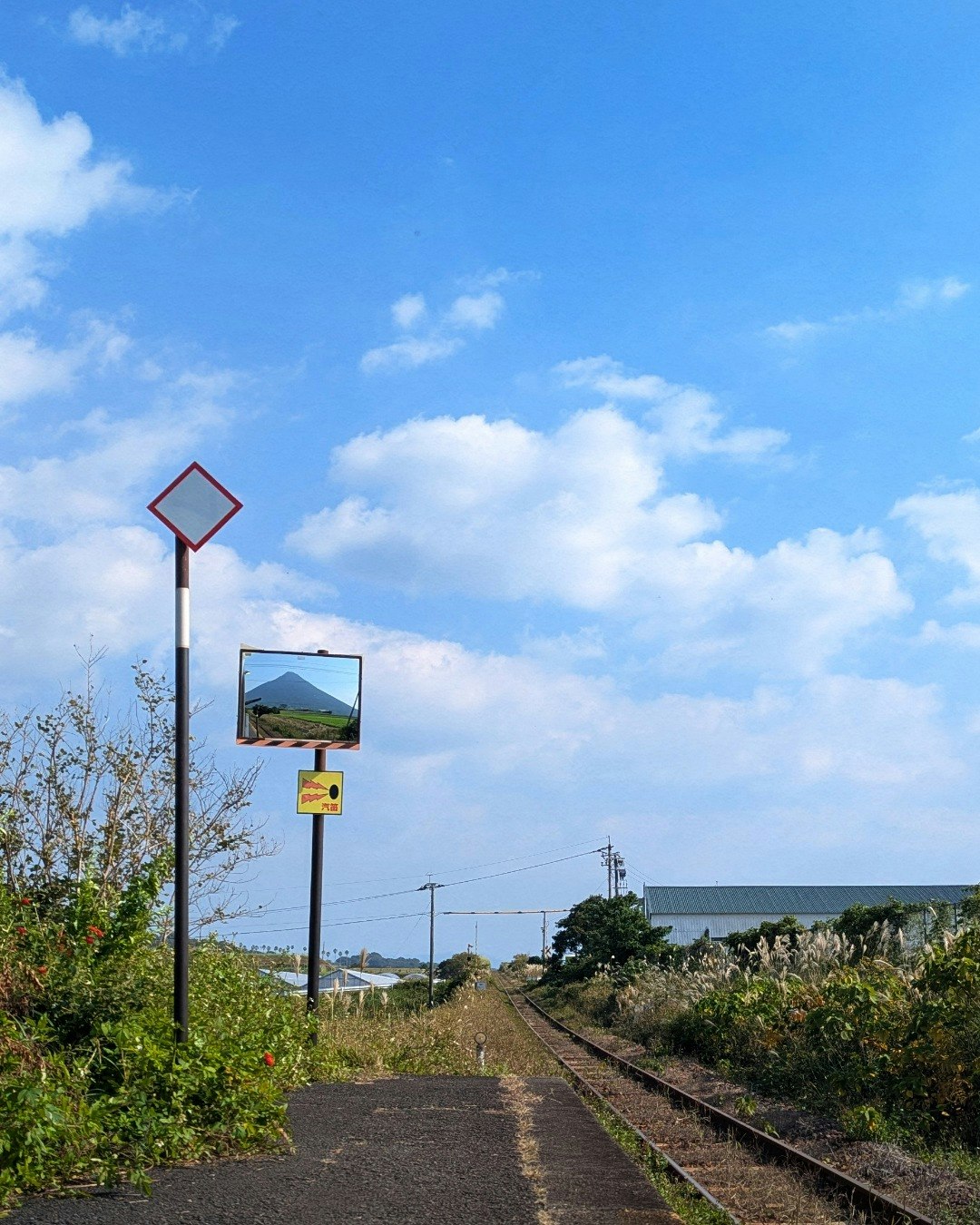線路と駅の標識が並ぶ鹿児島県西大山駅のホームの先の空と雲