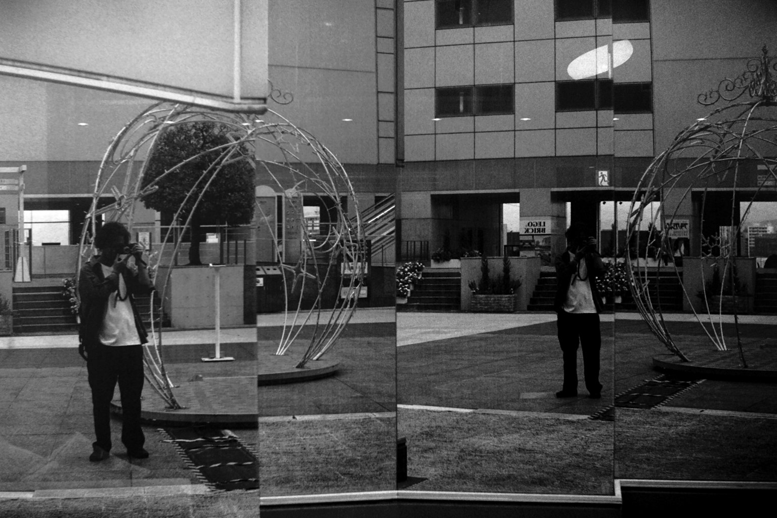 Person steht in einem monochromen Raum mit einer Metallskulptur eines Globus