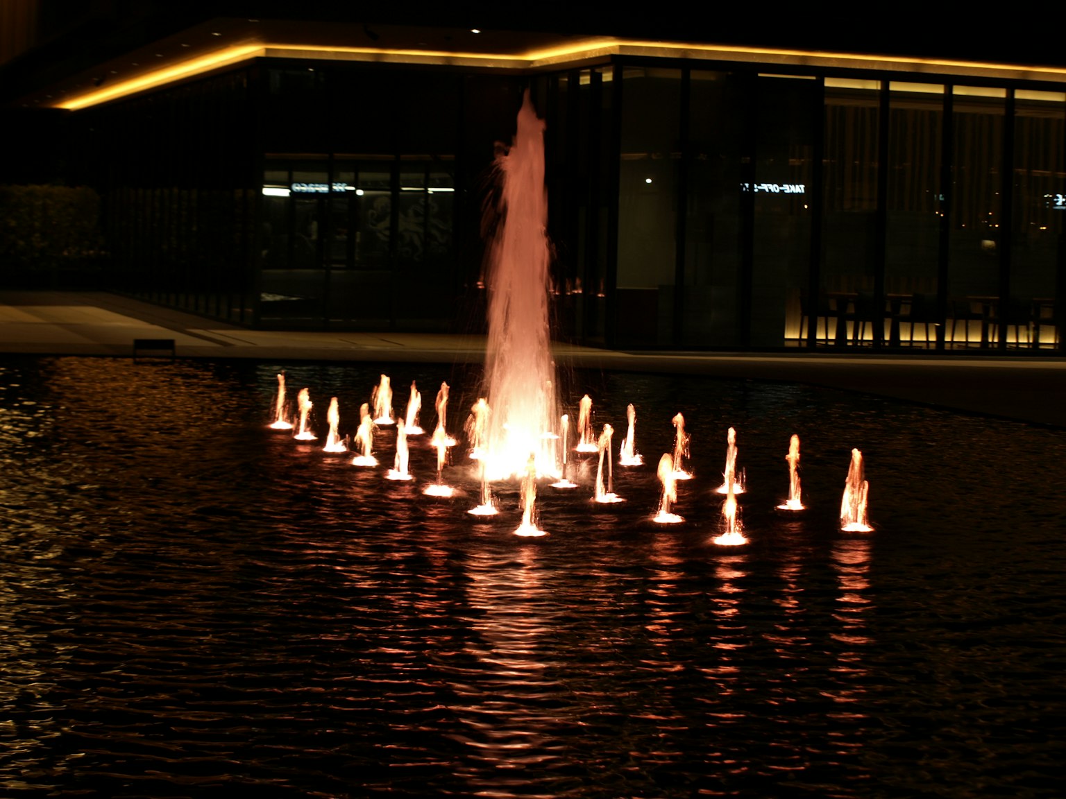 Beleuchteter Brunnen mit umliegenden Lichtern bei Nacht