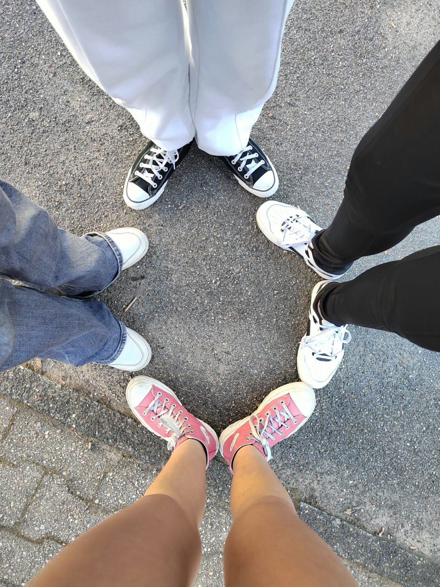 Une photo montrant quatre paires de pieds formant un cercle des baskets roses sont proéminentes