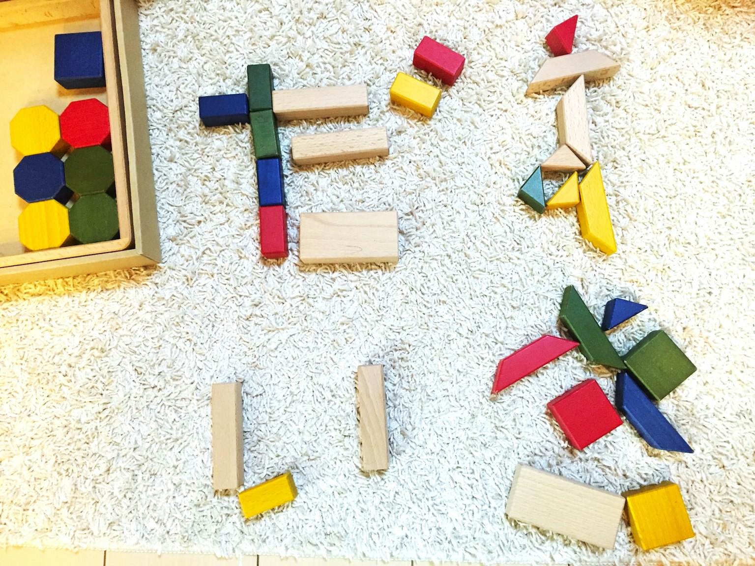 Colorful building blocks arranged on a white carpet forming letters