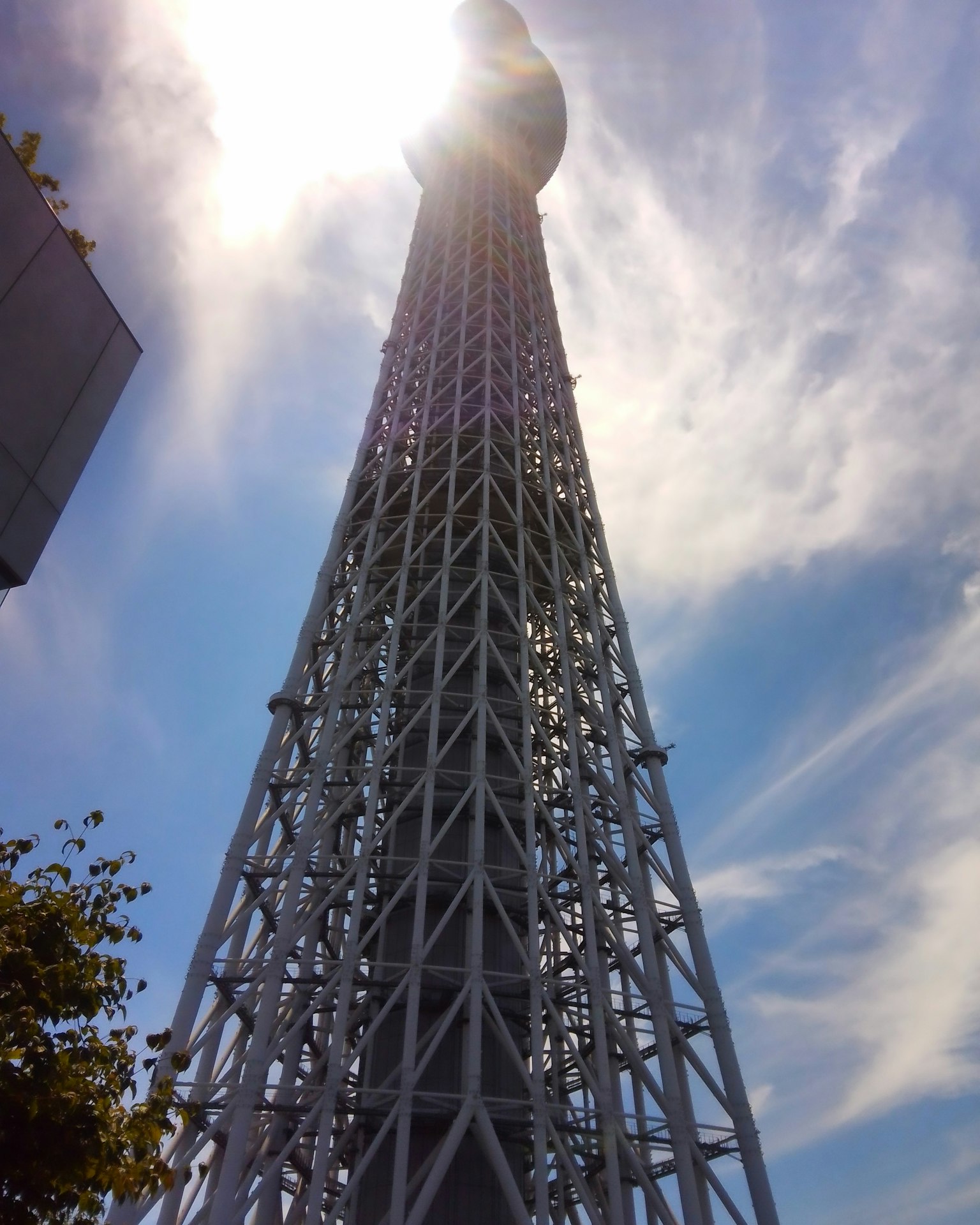 Vista della Tokyo Skytree dal basso con il sole che brilla in cima