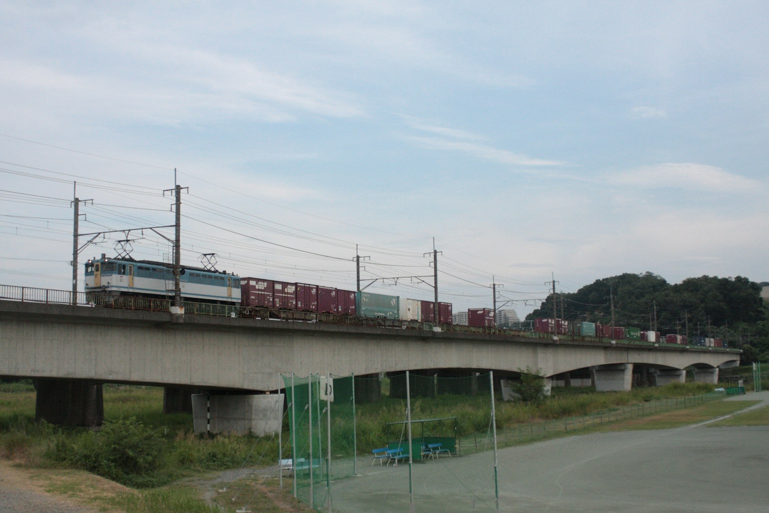 货运列车穿过桥梁，背景为蓝天和绿色田野