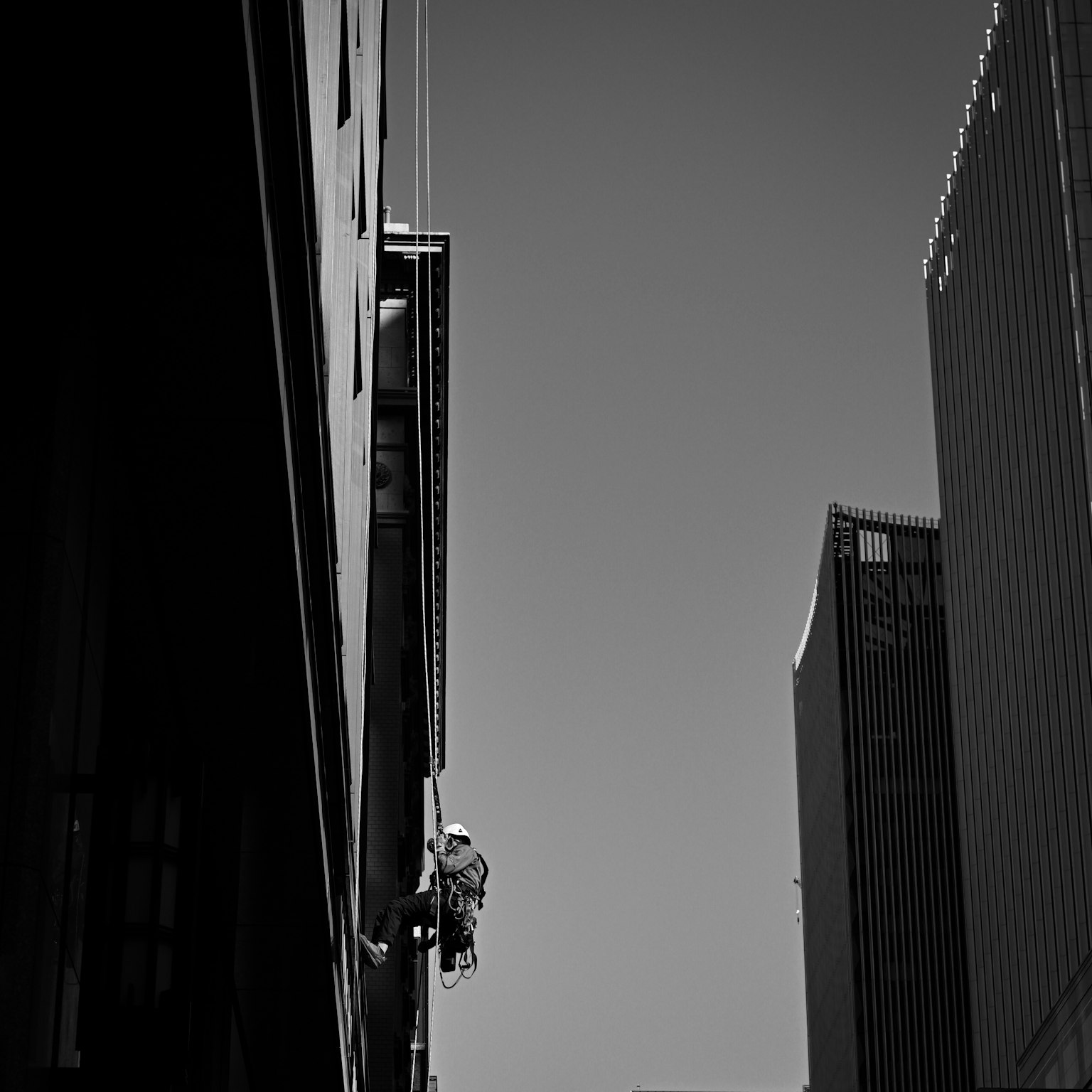 Immagine in bianco e nero di un lavoratore che scala un muro di un edificio