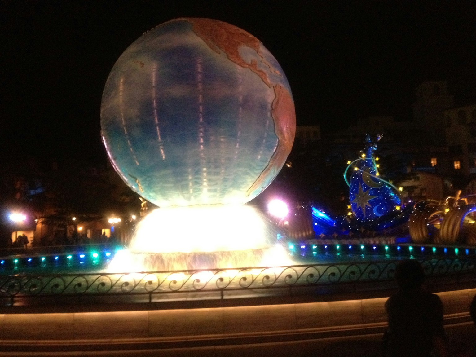 Grande sfera illuminata in una fontana di notte con decorazioni blu