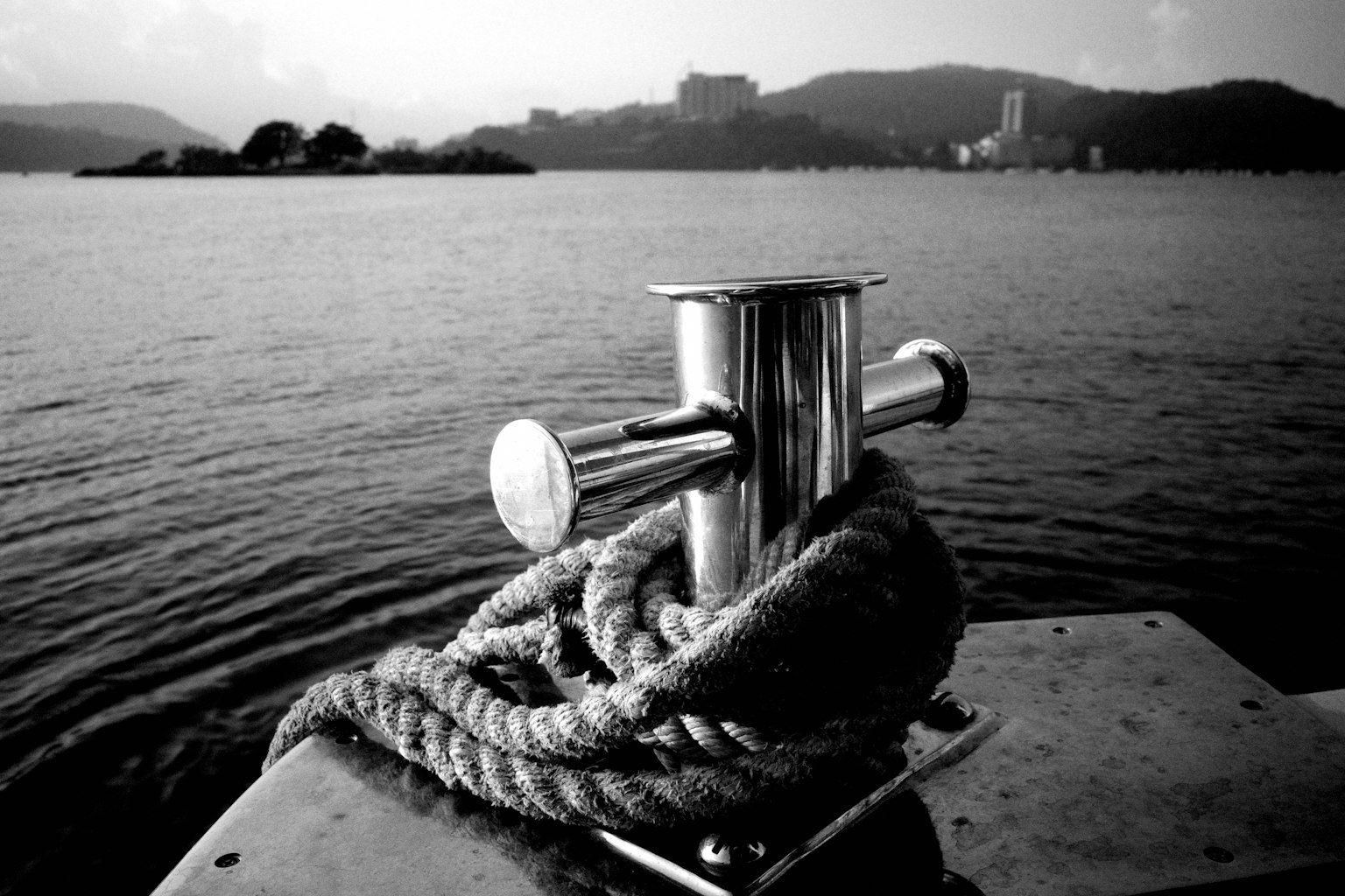 คลีตเรือโลหะพร้อมเชือกบนพื้นหลังน้ำในขาวดำ