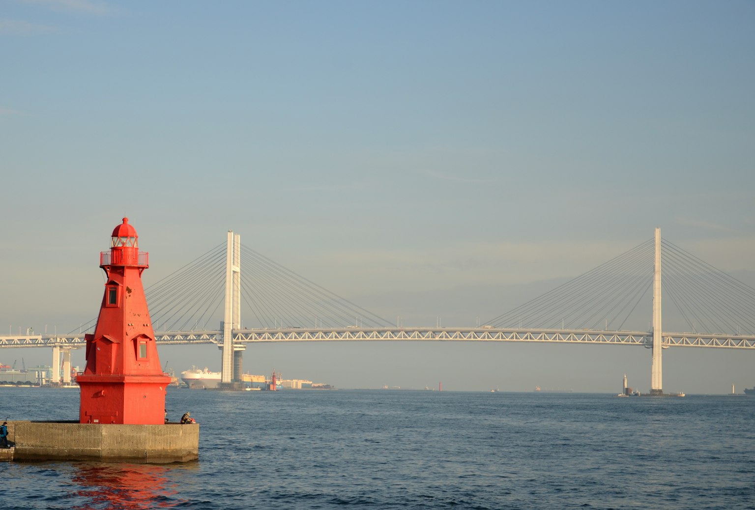 Faro rosso vicino a un ponte su acque calme