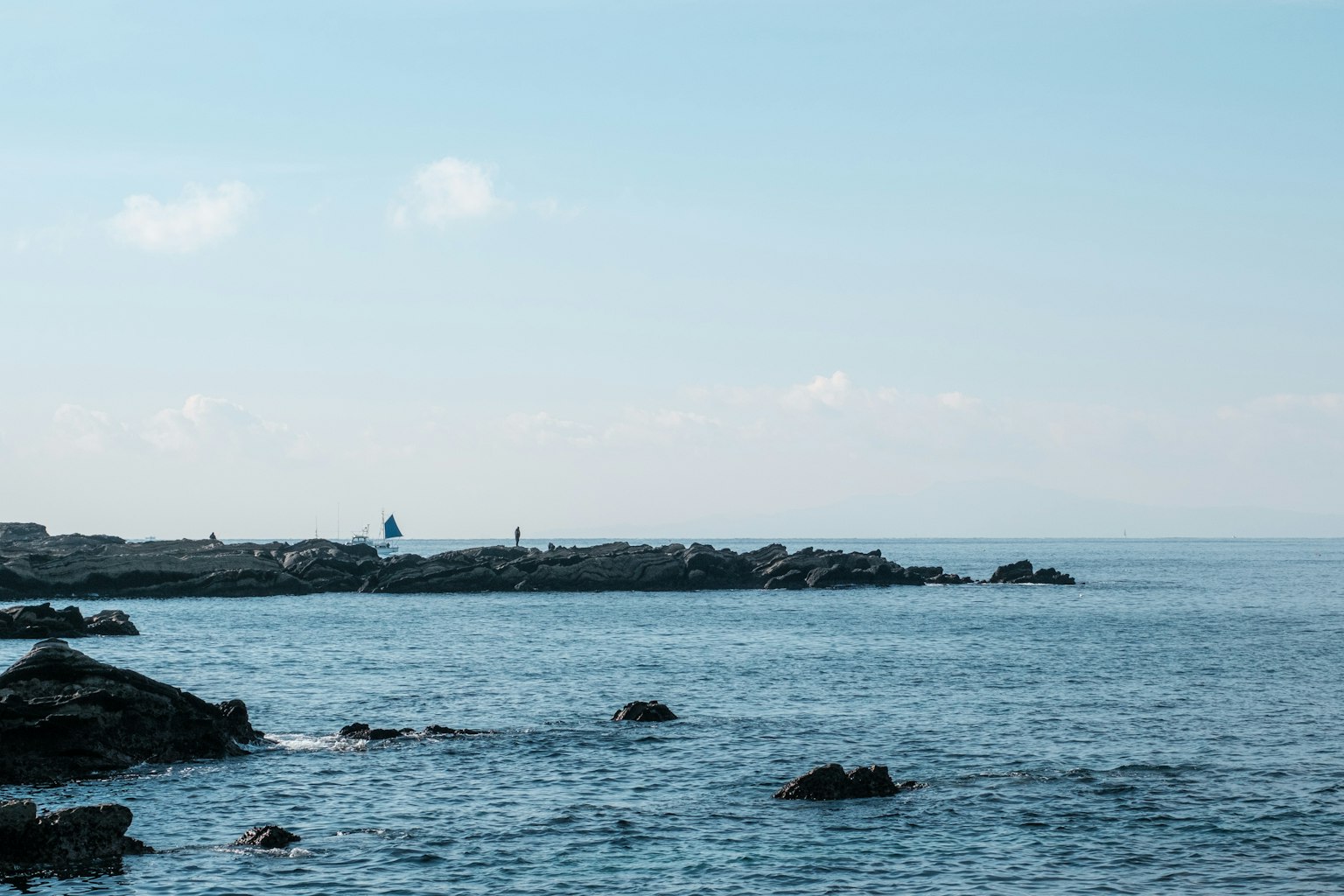 海岸景观，蓝天和宁静的水面，靠近岩石海岸