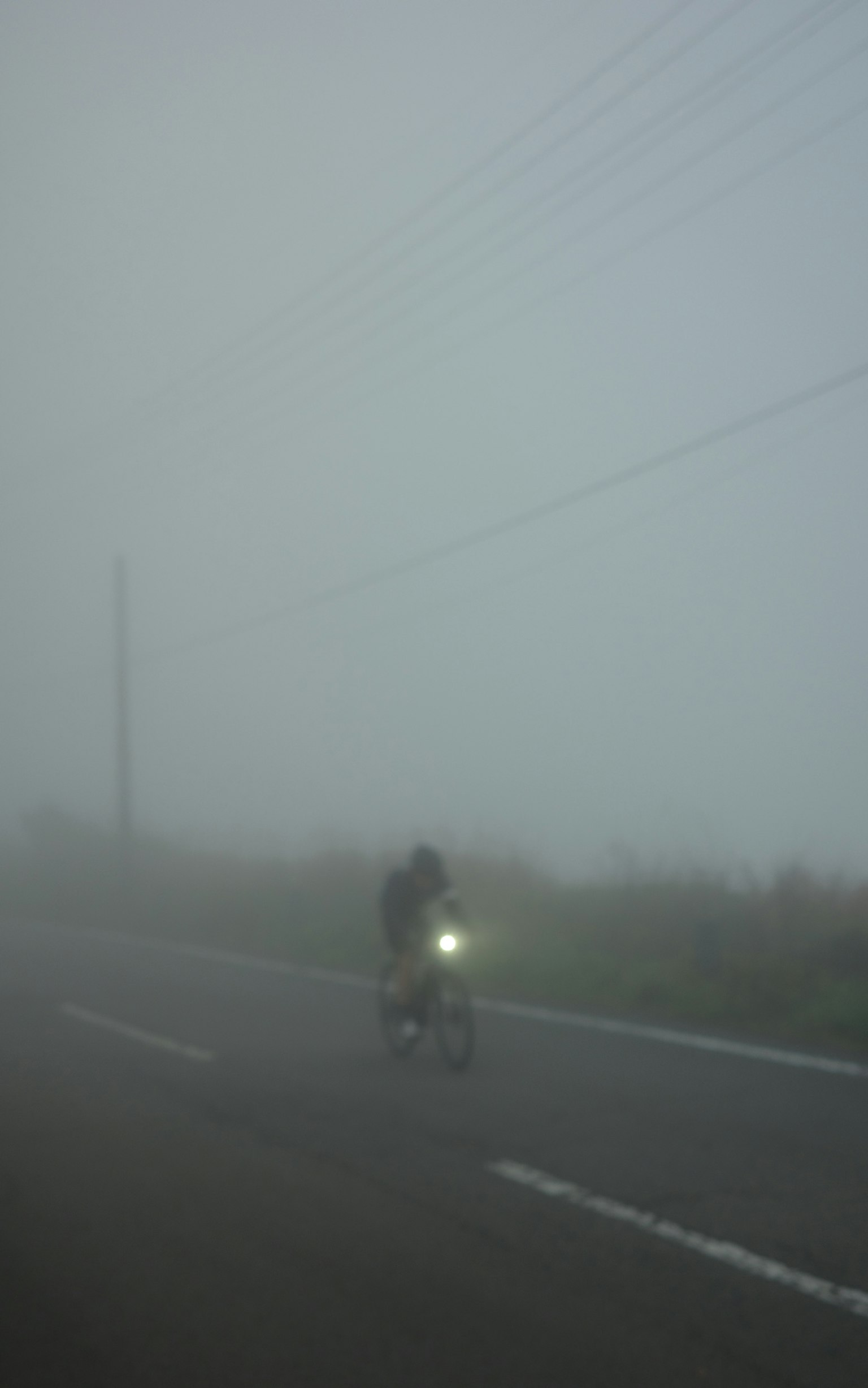霧の中を走る自転車と暗い道路の風景