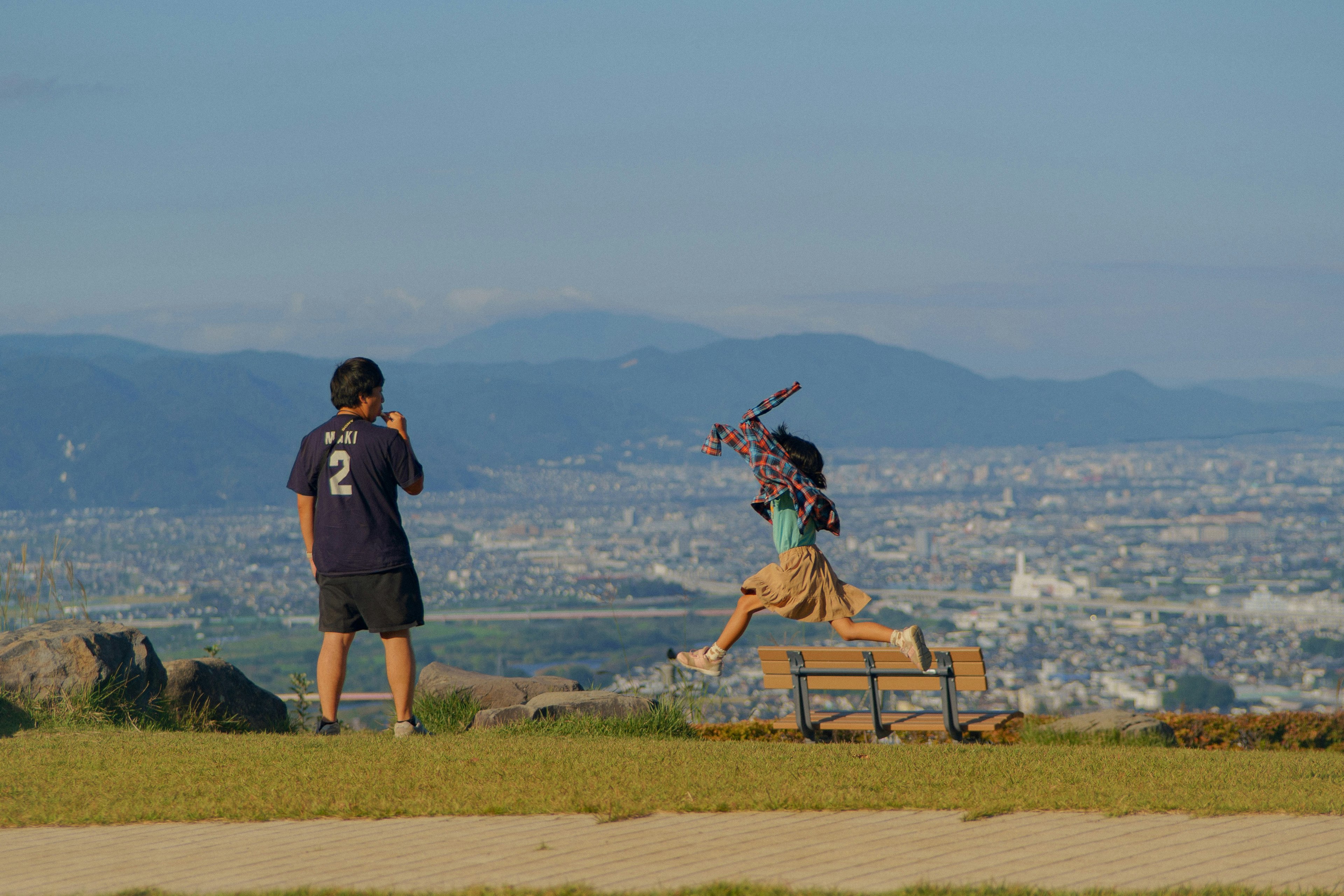 丘の上でギターを弾く人とベンチのある景色
