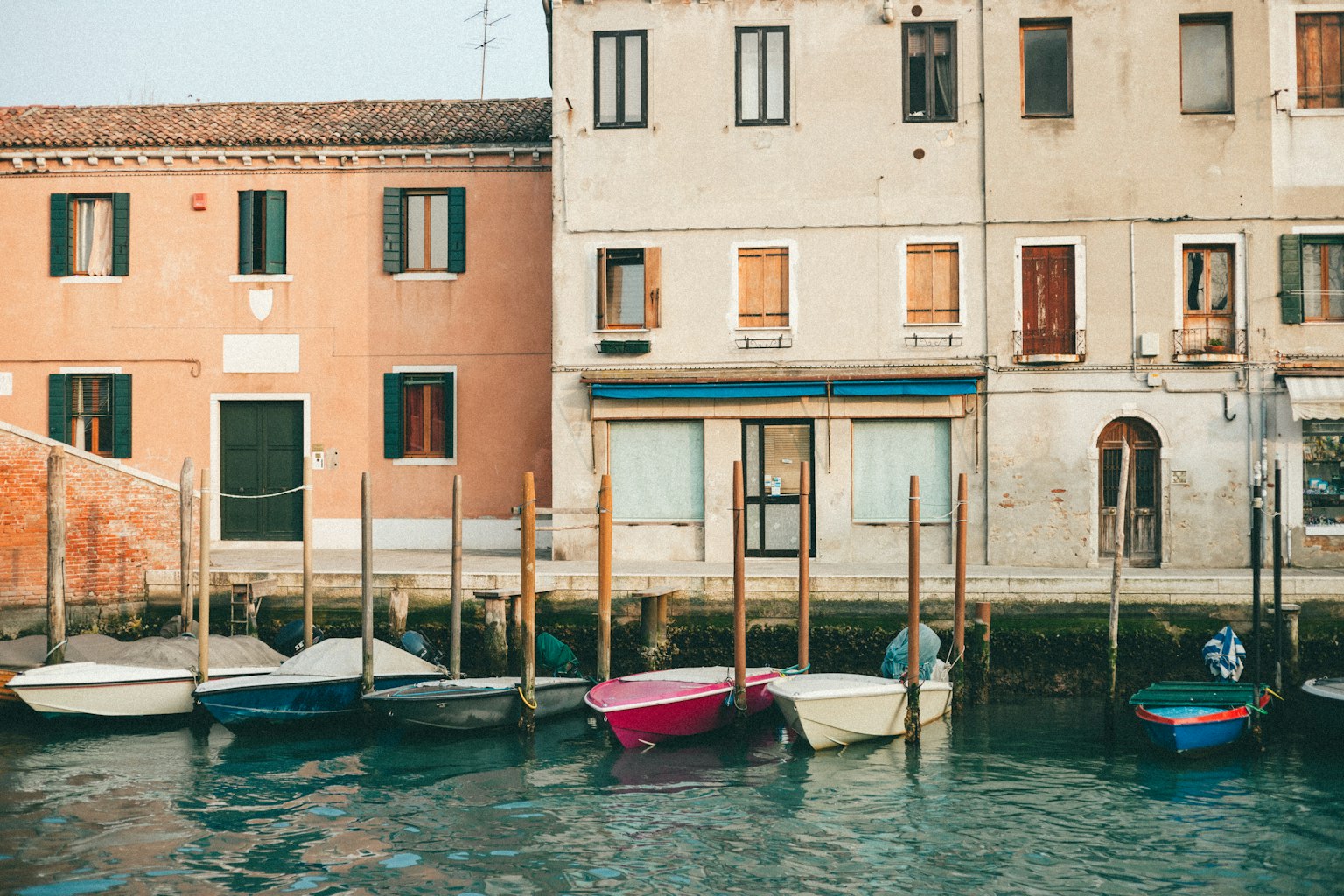 Barche colorate allineate lungo la riva con edifici antichi