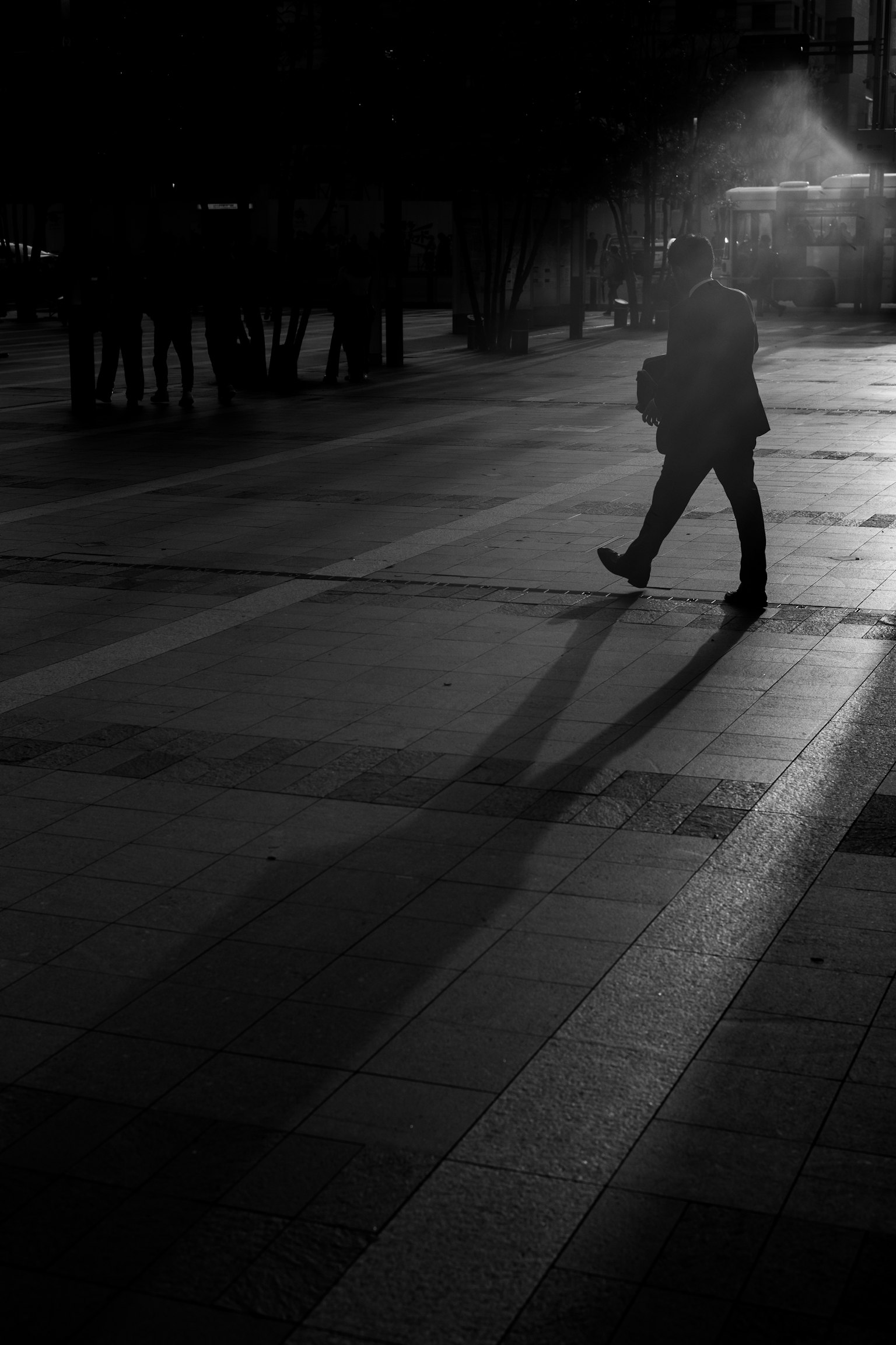 Silhouette di una persona che cammina in un ambiente urbano scuro con lunghe ombre