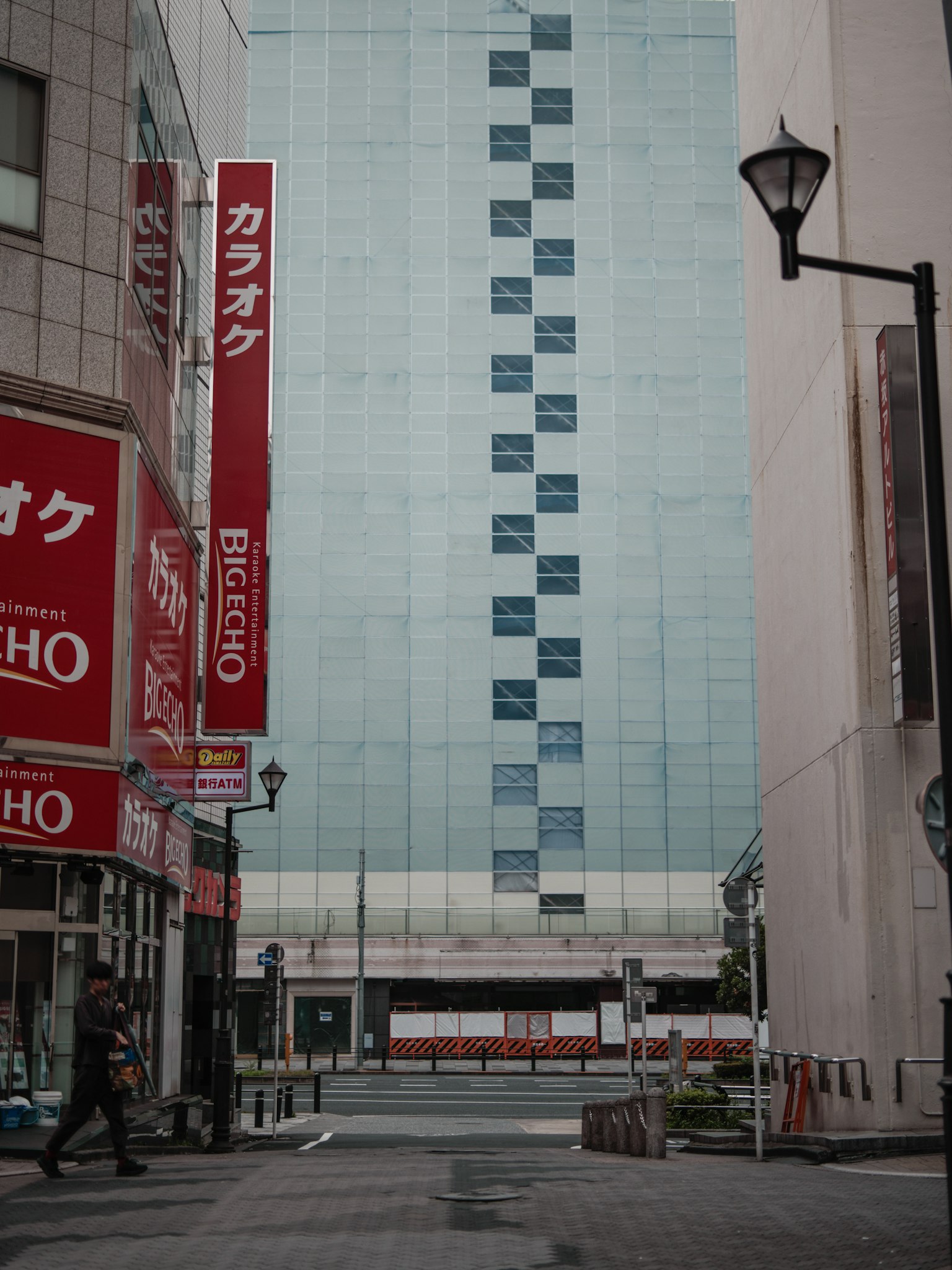 Straßenansicht mit einem Gebäude aus blauer Glasfassade und roten Schildern