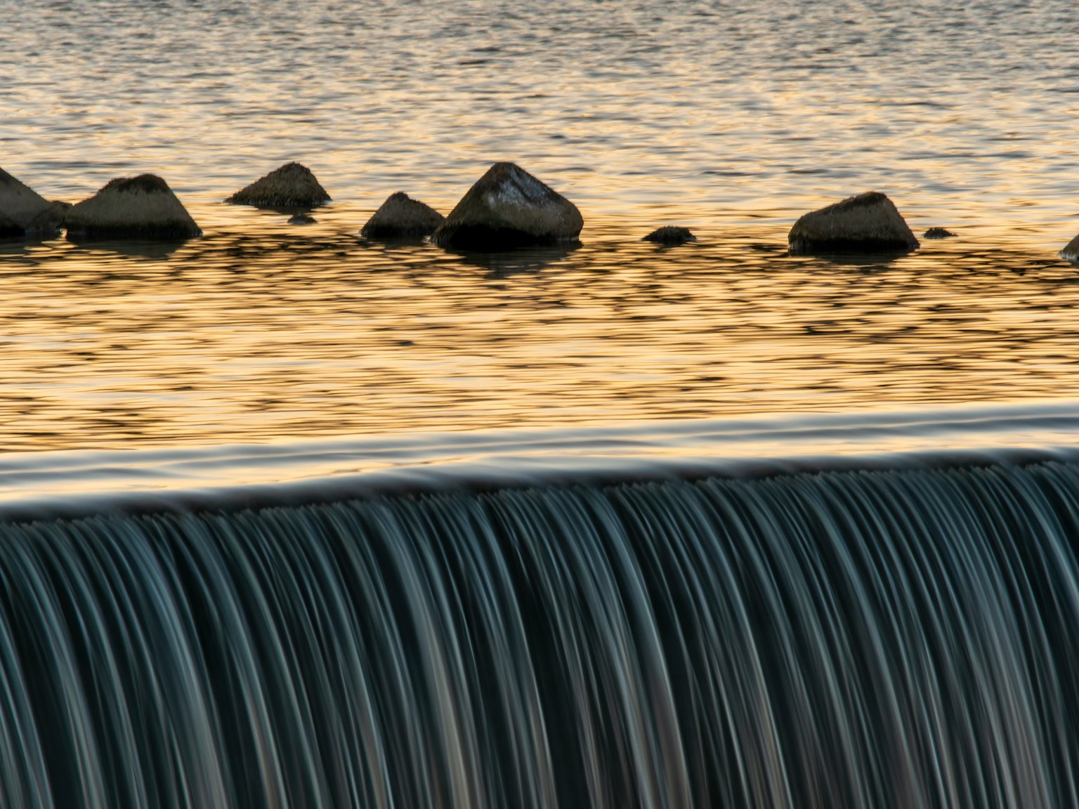 Acqua che scorre su rocce con belle riflessioni del tramonto