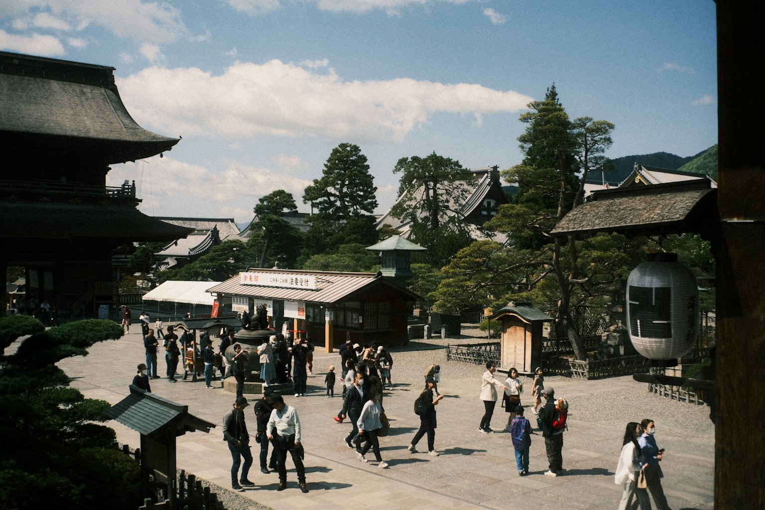 A bustling temple courtyard with tourists and surrounding scenery