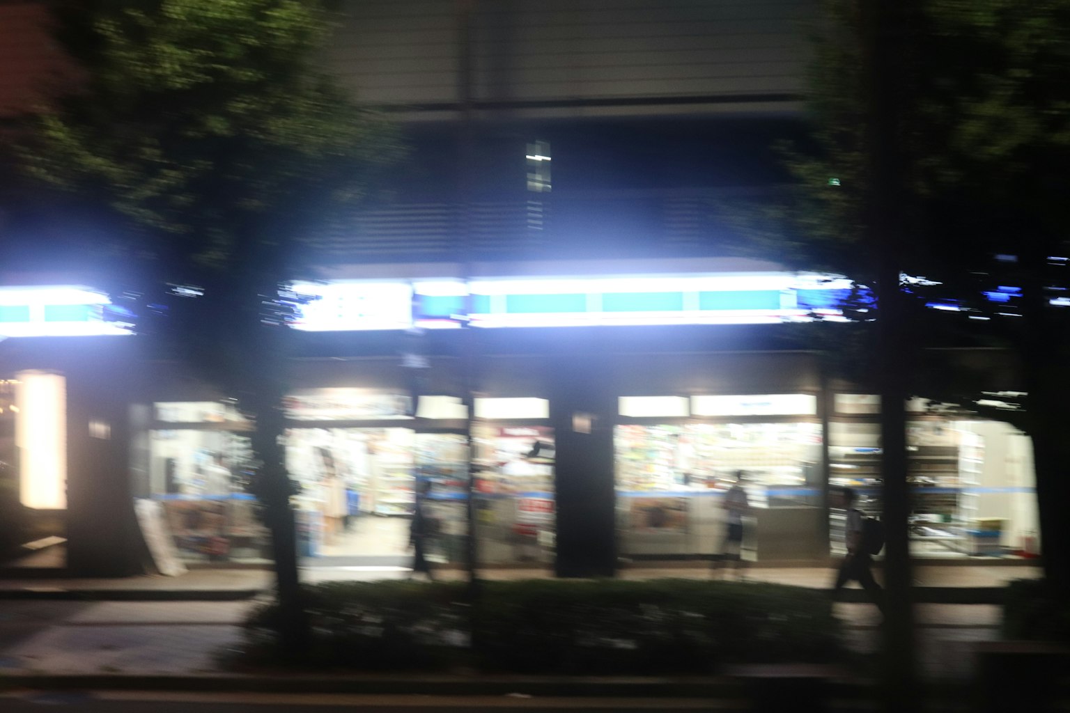 夜间便利店的外观明亮的招牌和街边的树木