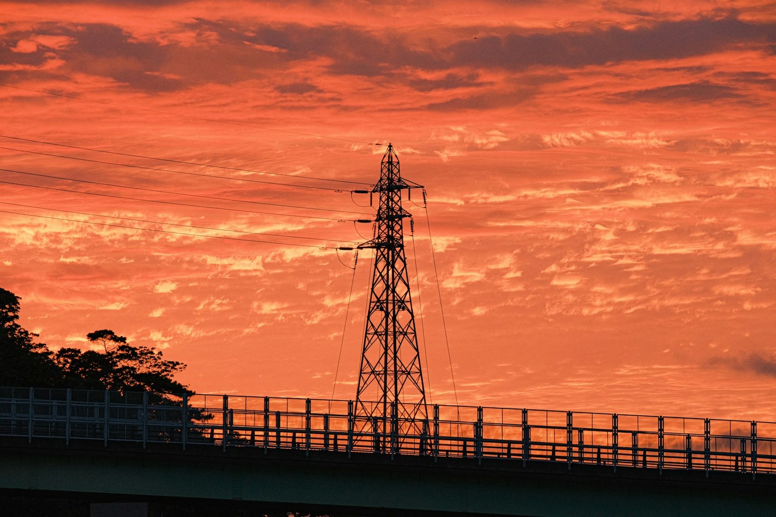夕陽下的輸電塔和橋的輪廓