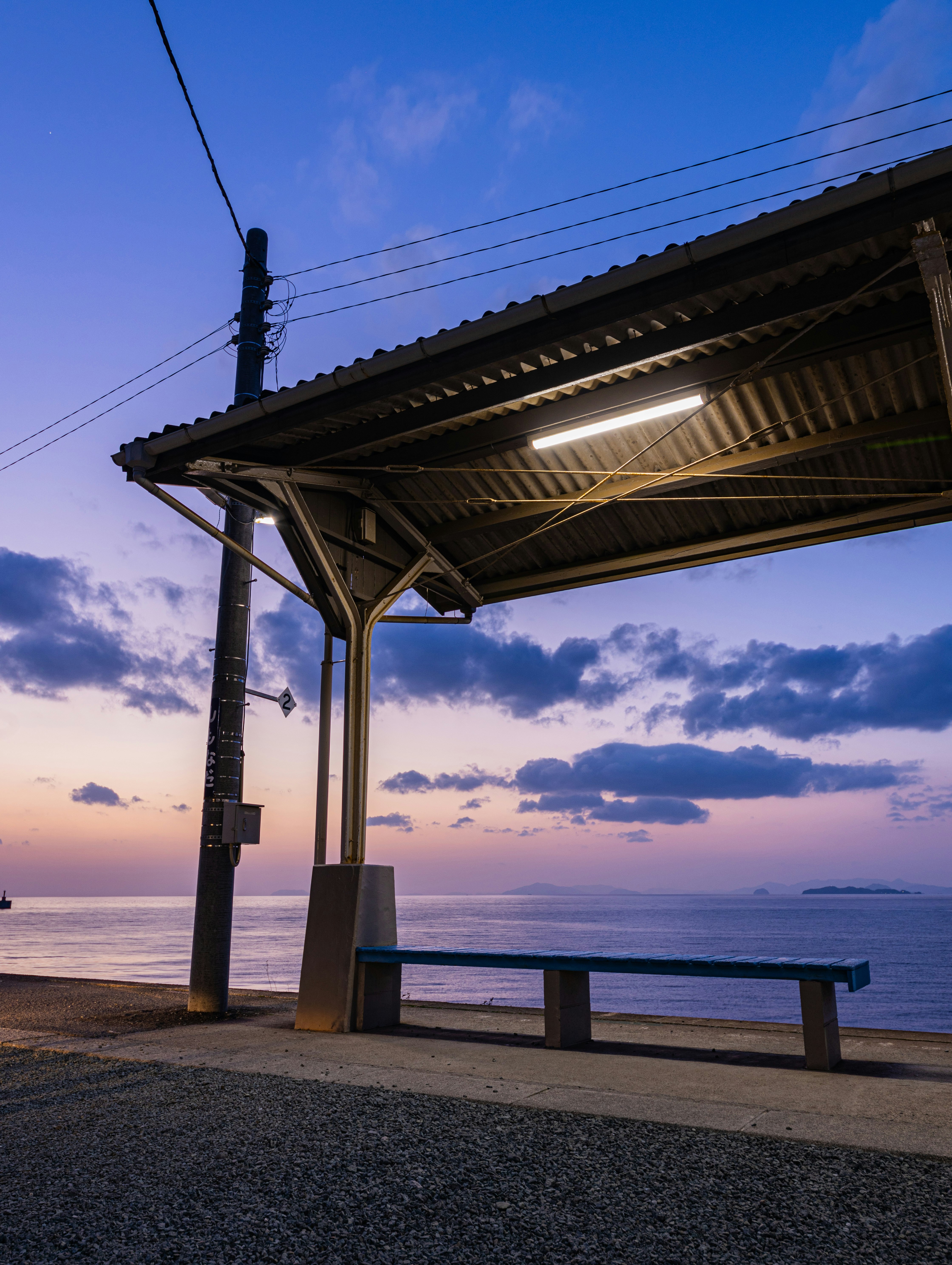 海辺のベンチがある屋根付き休憩所と夕焼け空