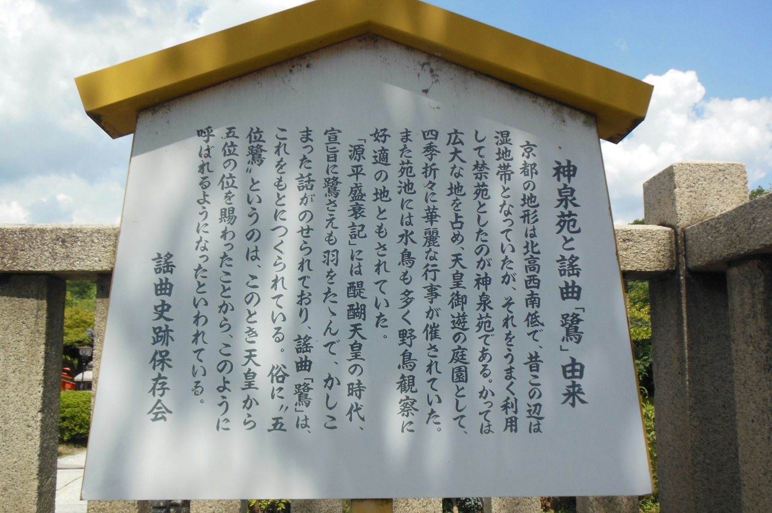 Panel informativo con texto en japonés y cielo azul de fondo