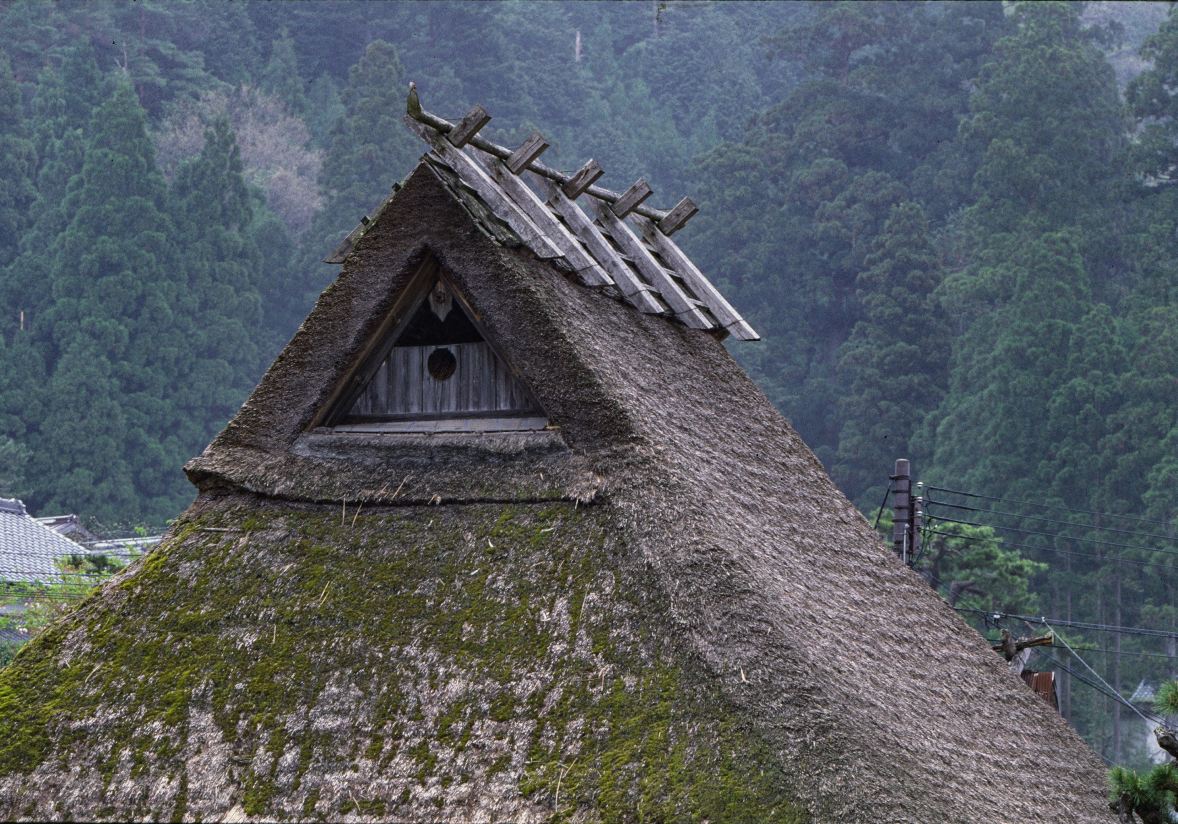 茅葺き屋根の三角屋根と周囲の山並み