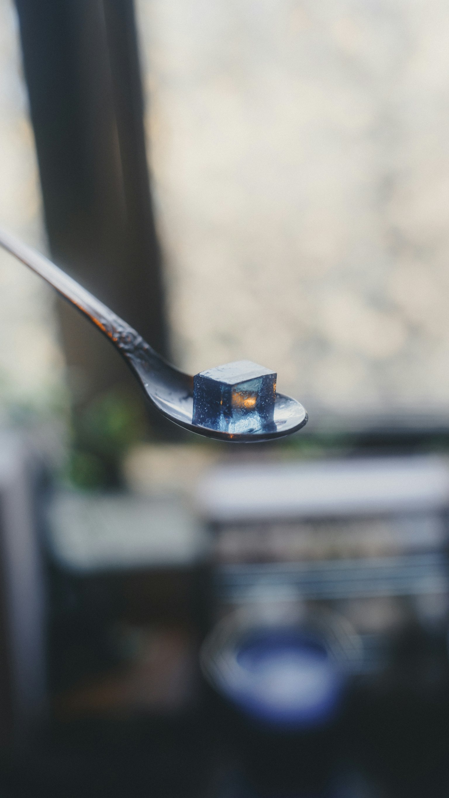 スプーンの上に乗った青いゼリーの塊とぼんやりした背景