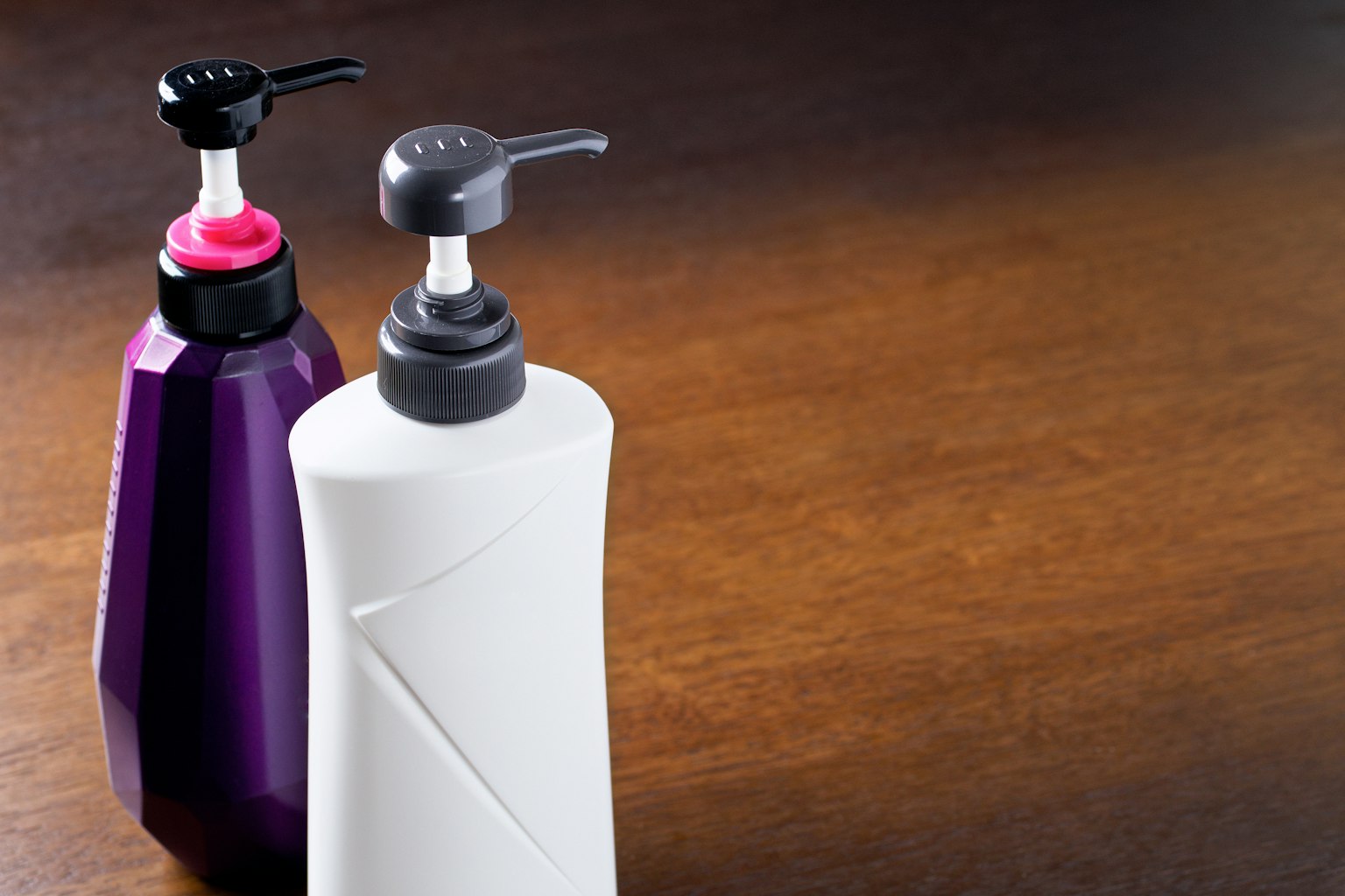 Botellas de bomba blancas y moradas colocadas sobre una mesa de madera