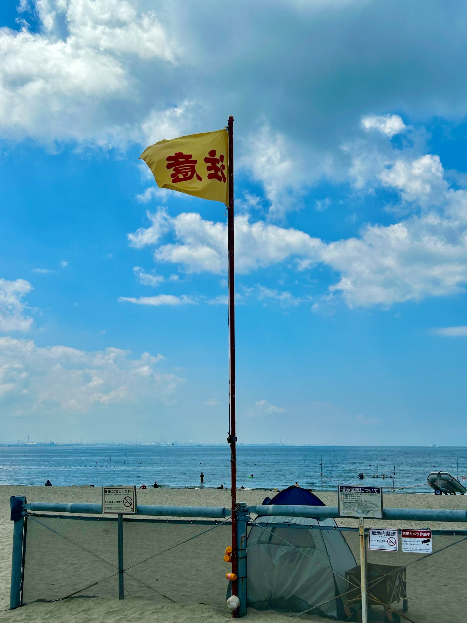 Yellow flag waving under blue sky at the beach