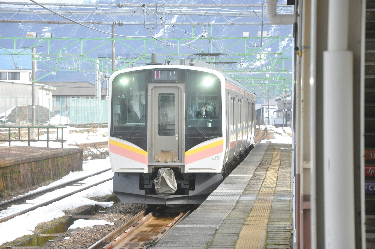Treno in arrivo in una stazione innevata con sfondo rurale