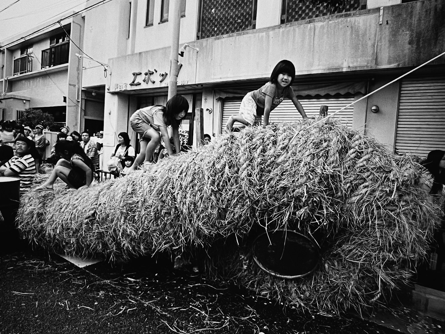 Children playing on a large pile of straw during a festival