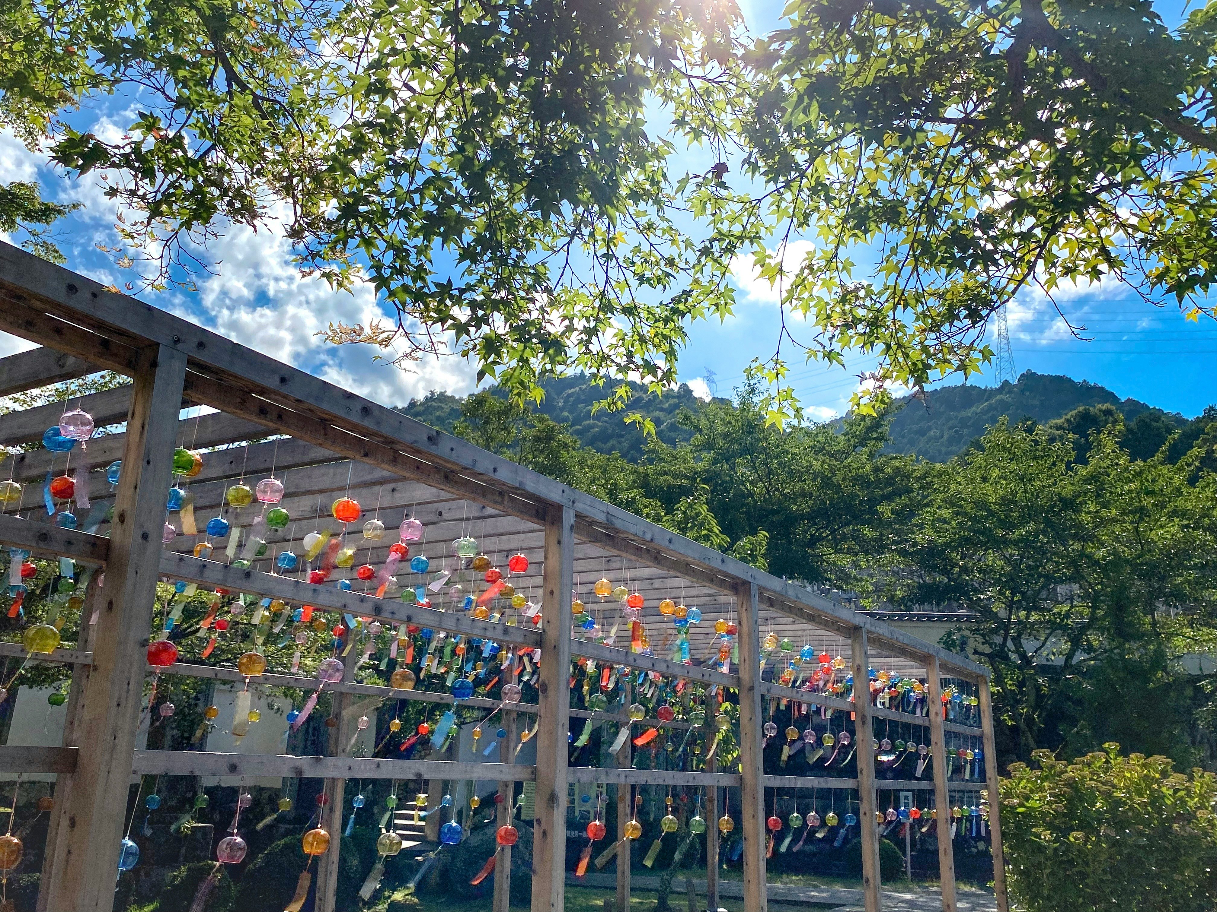 風鈴が並ぶ木製の回廊と夏の青空