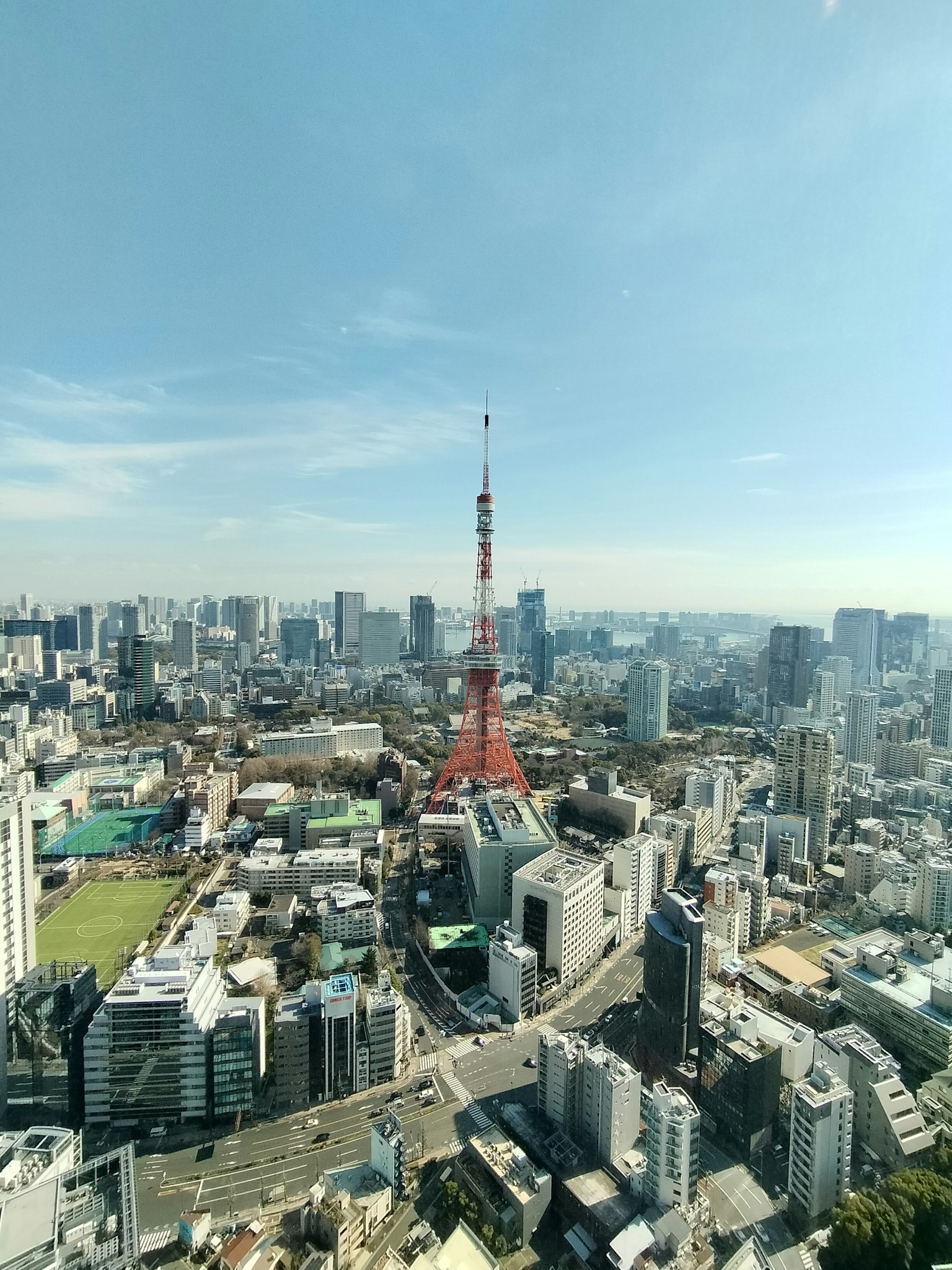 Pemandangan udara Menara Tokyo dikelilingi oleh pemandangan kota langit biru dan gedung pencakar langit
