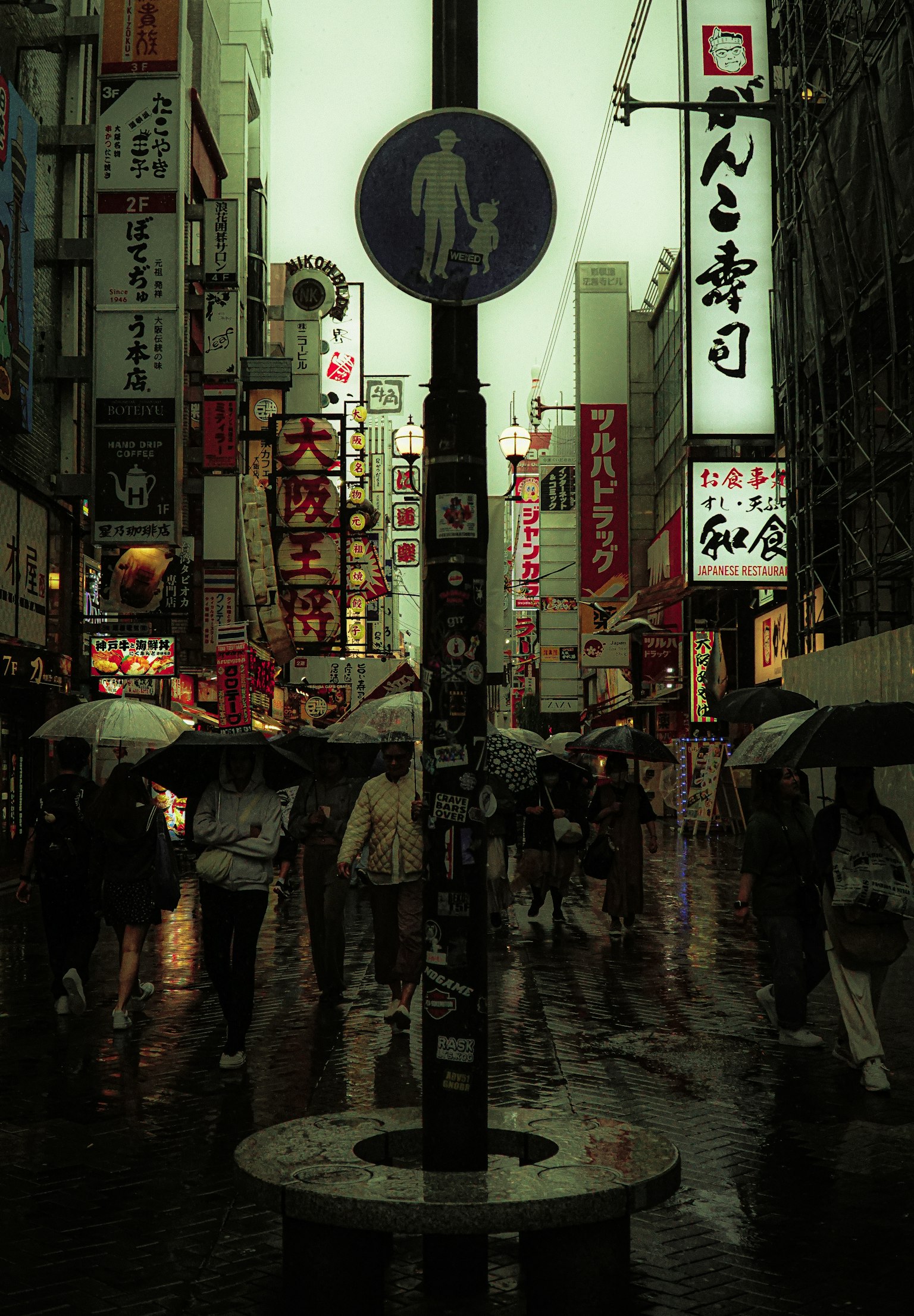 雨の中の人々と看板が並ぶ街並み
