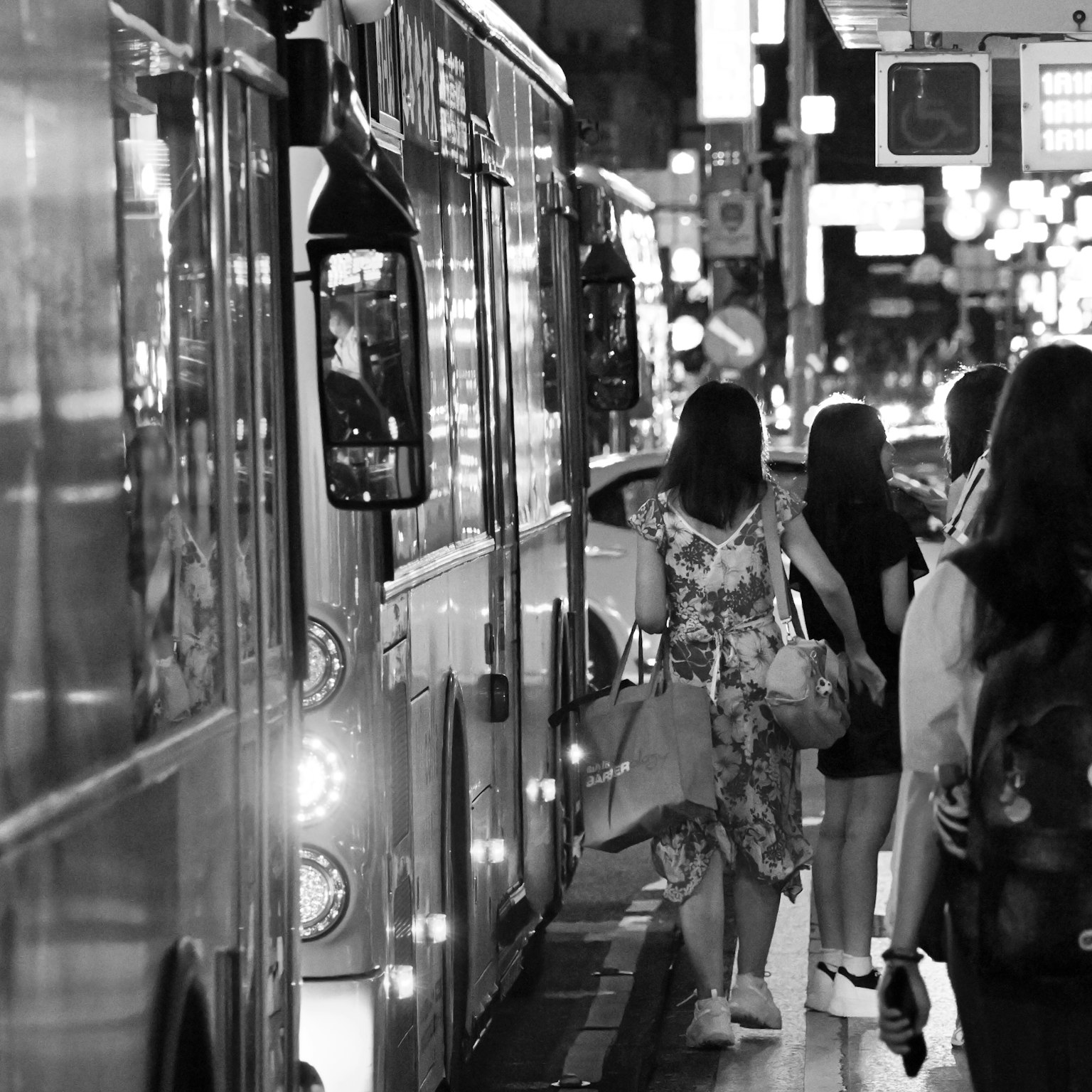 Mujeres caminando en una calle de la ciudad por la noche con autobuses