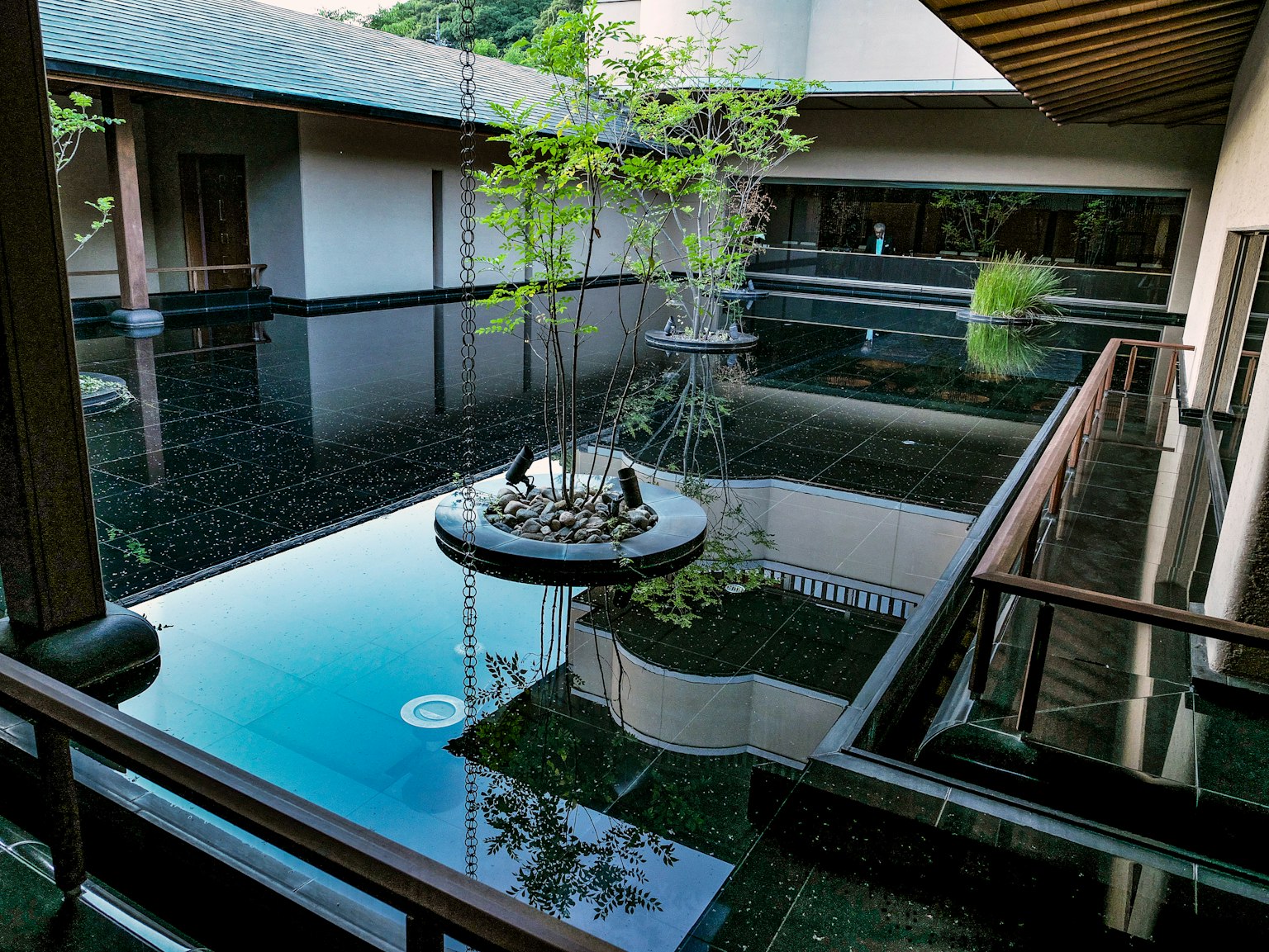 Cortile tranquillo di giardino giapponese con superficie d'acqua riflettente e vegetazione