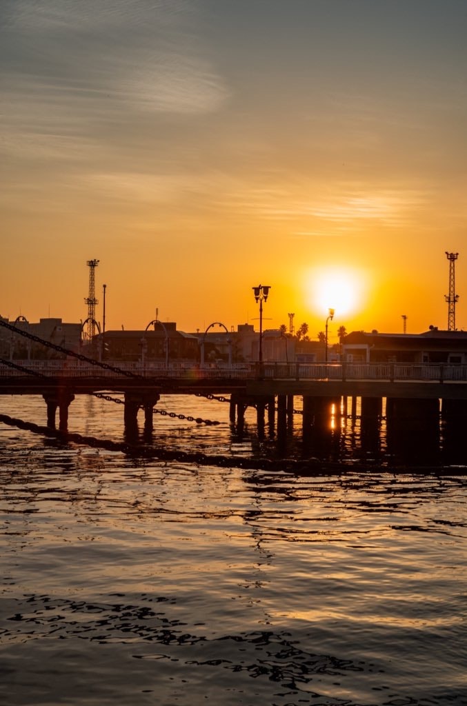 dermaga pelabuhan saat matahari terbenam dengan pantulan di air