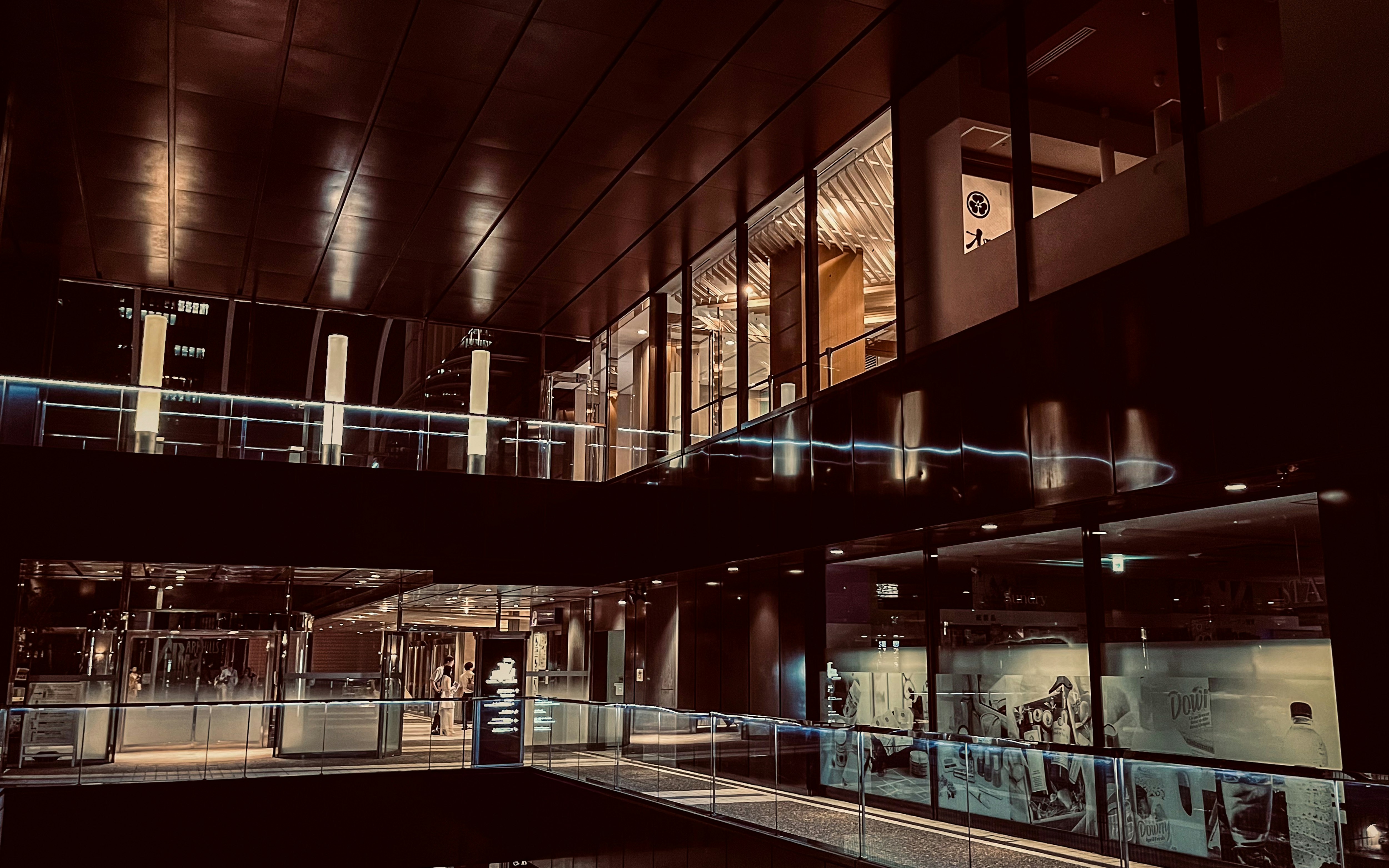 nighttime city buildings and light reflections along an elevated walkway