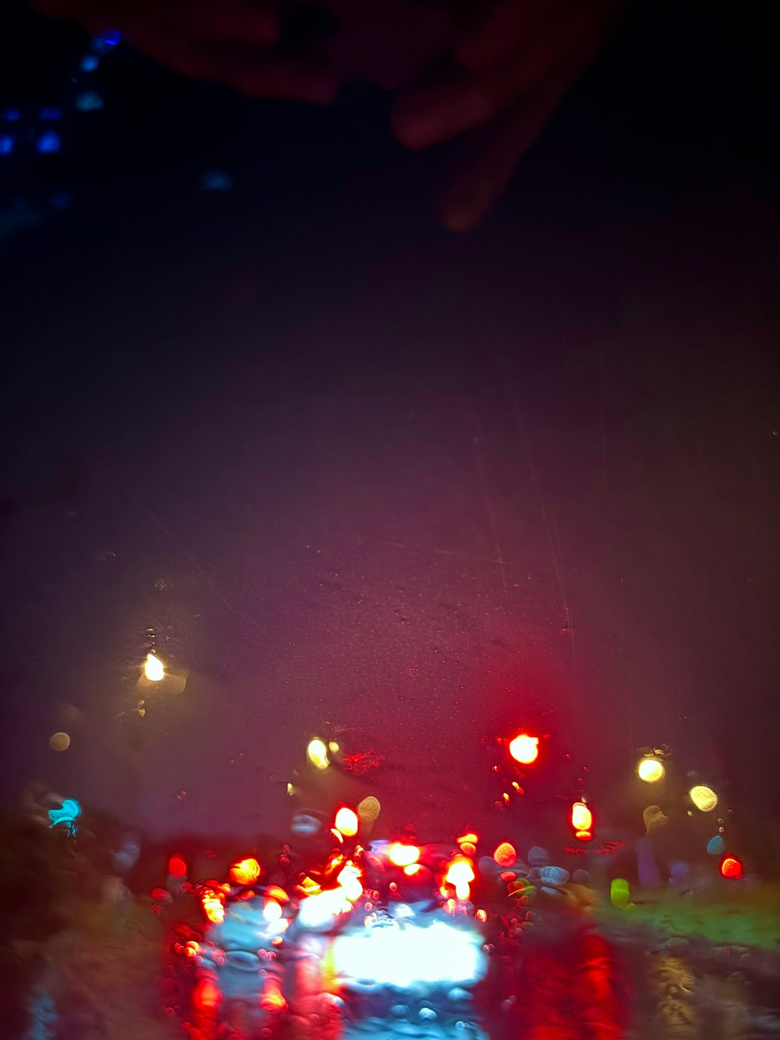 Vista borrosa de las luces traseras de los coches y farolas bajo la lluvia
