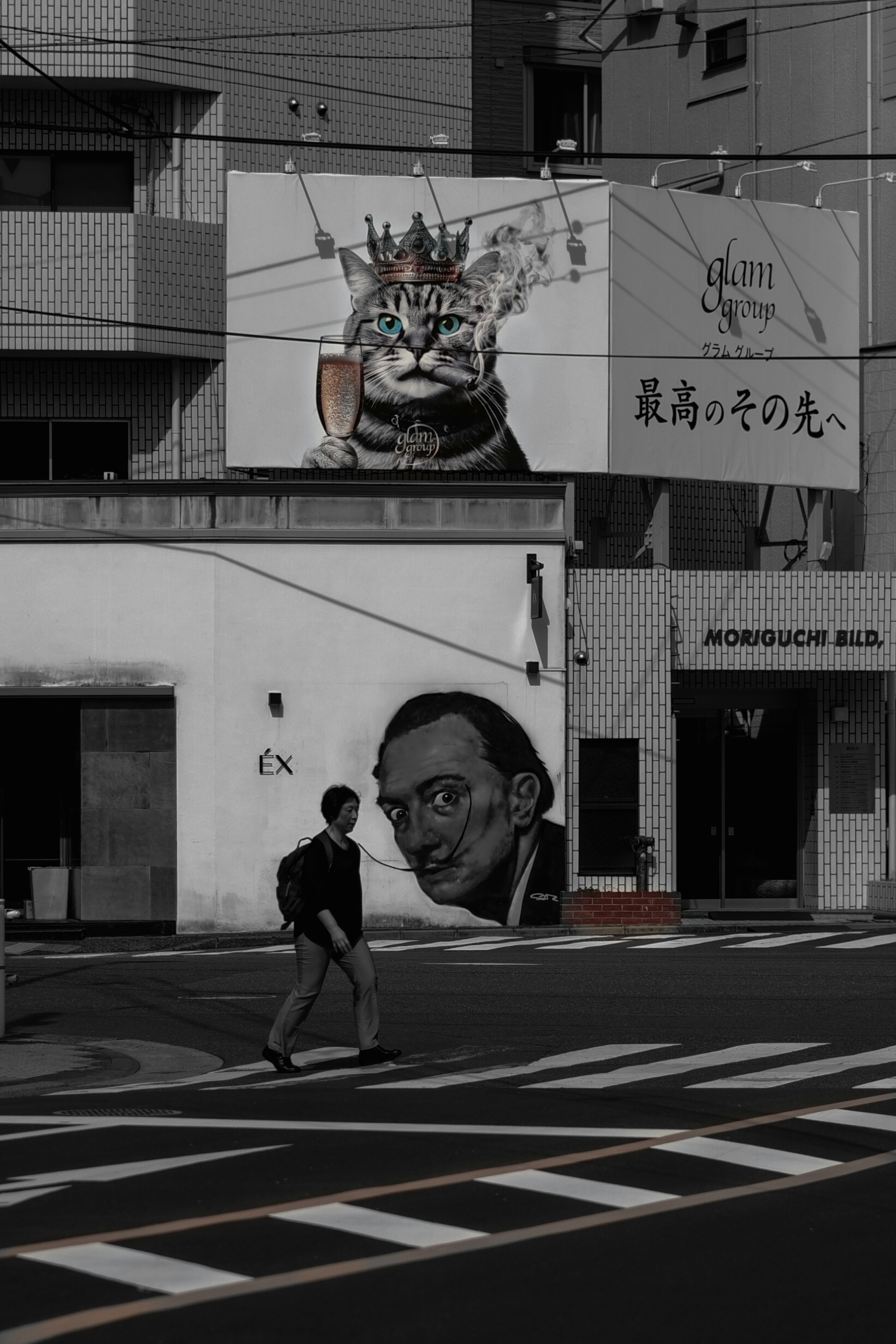 路地の壁に描かれた猫の巨大看板と交差点の歩行者